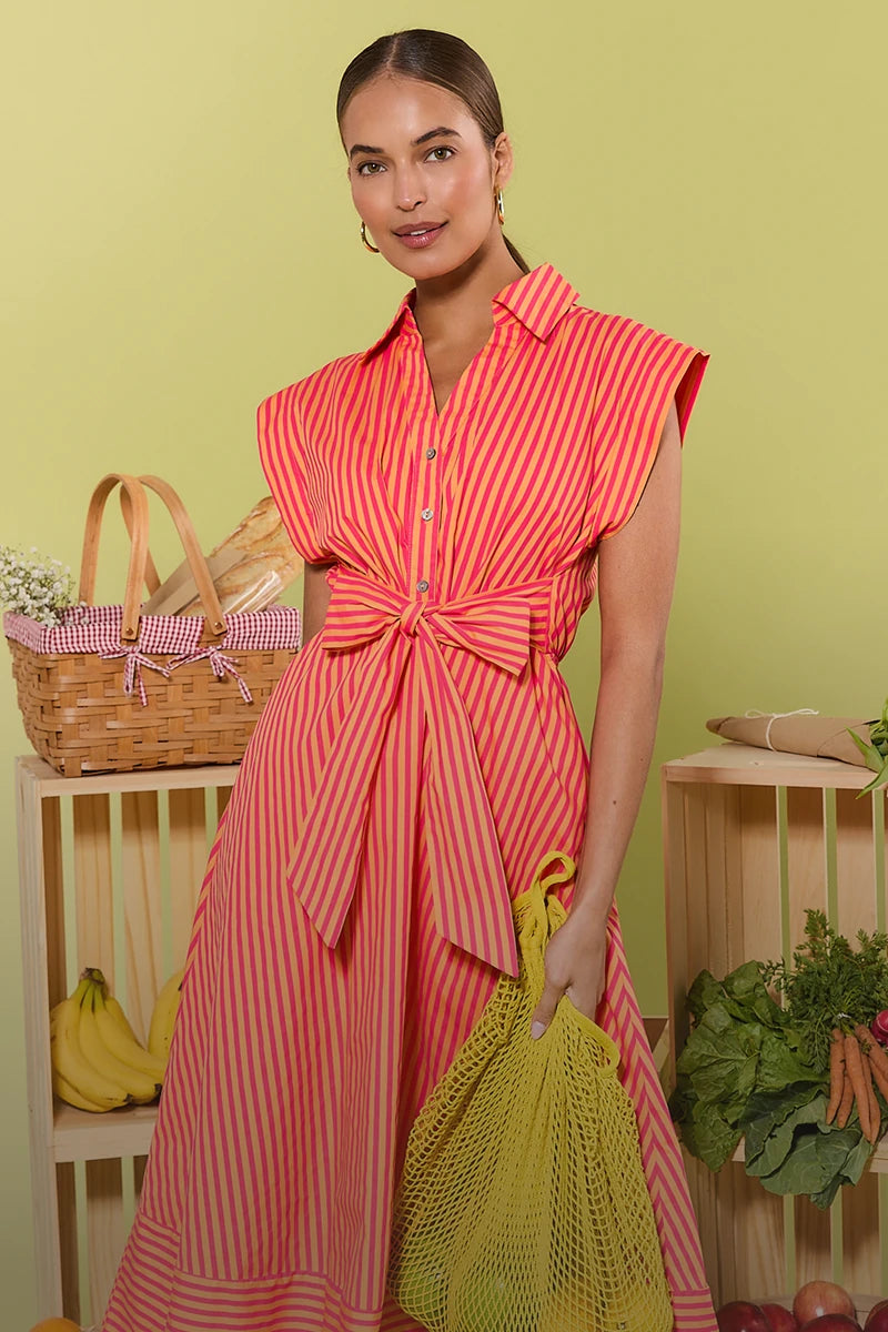 Woman in a red and white striped dress holding a yellow bag in a kitchen setting.