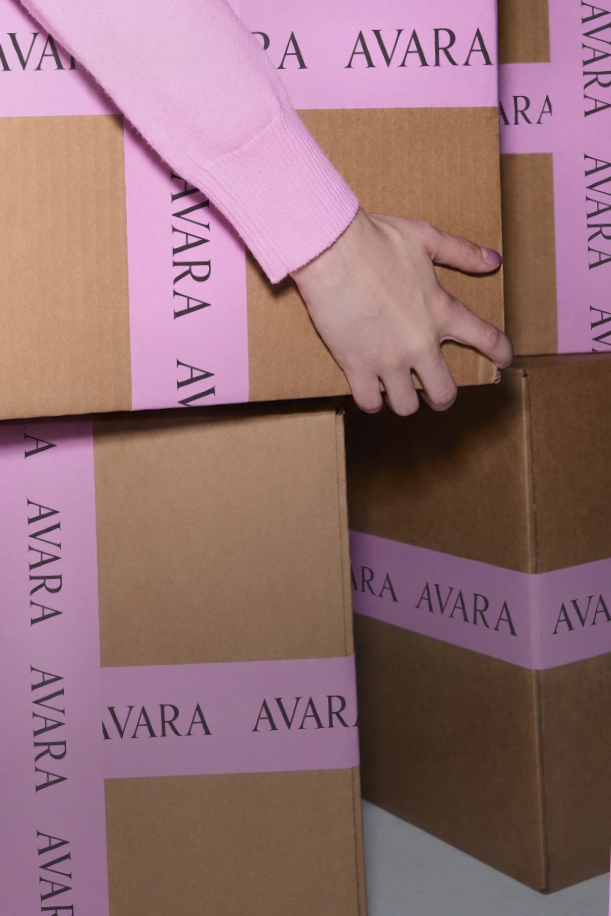 Cardboard boxes with 'Avara' branding and a hand reaching towards one of them. hero