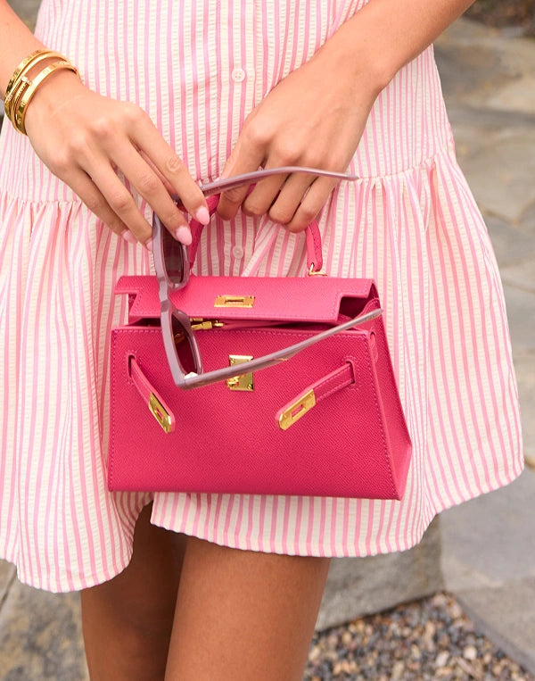 Person holding a pink handbag with a blurred background navigation