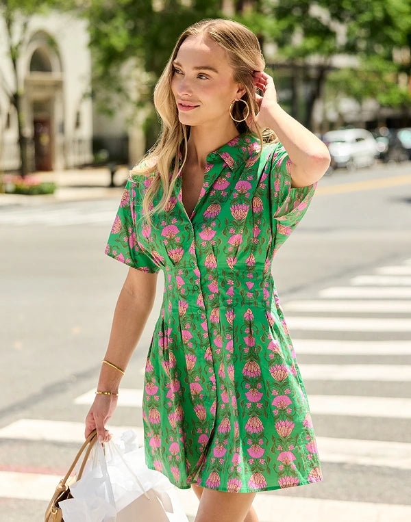 woman walking outside on crosswalk wearing a green and pink short dress