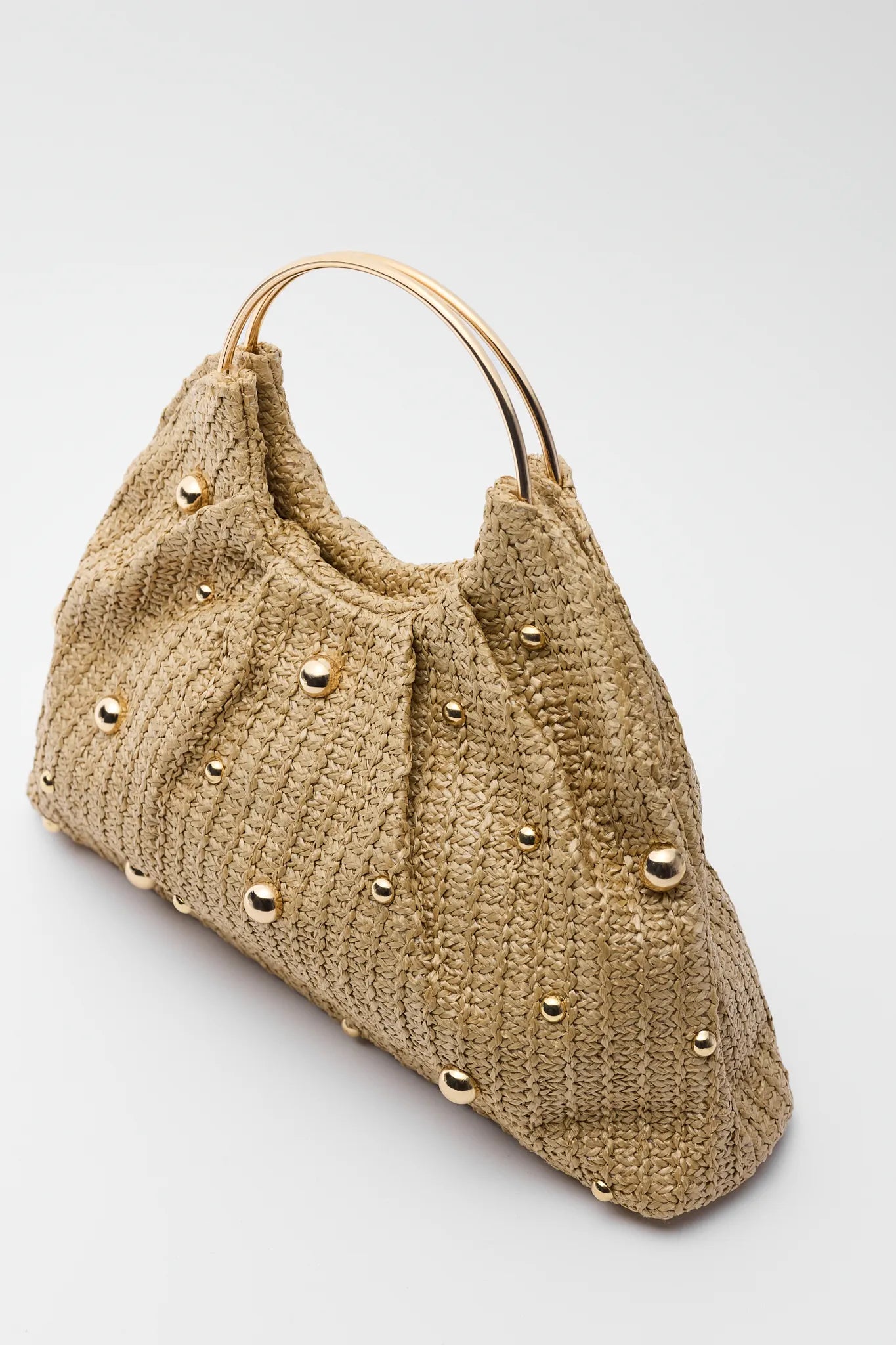 Beige handbag with gold studs on a light gray background