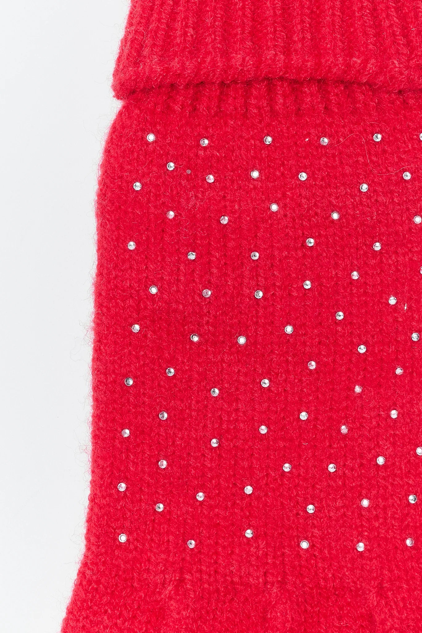 Close-up of a red knitted garment with small white dots on a light gray background