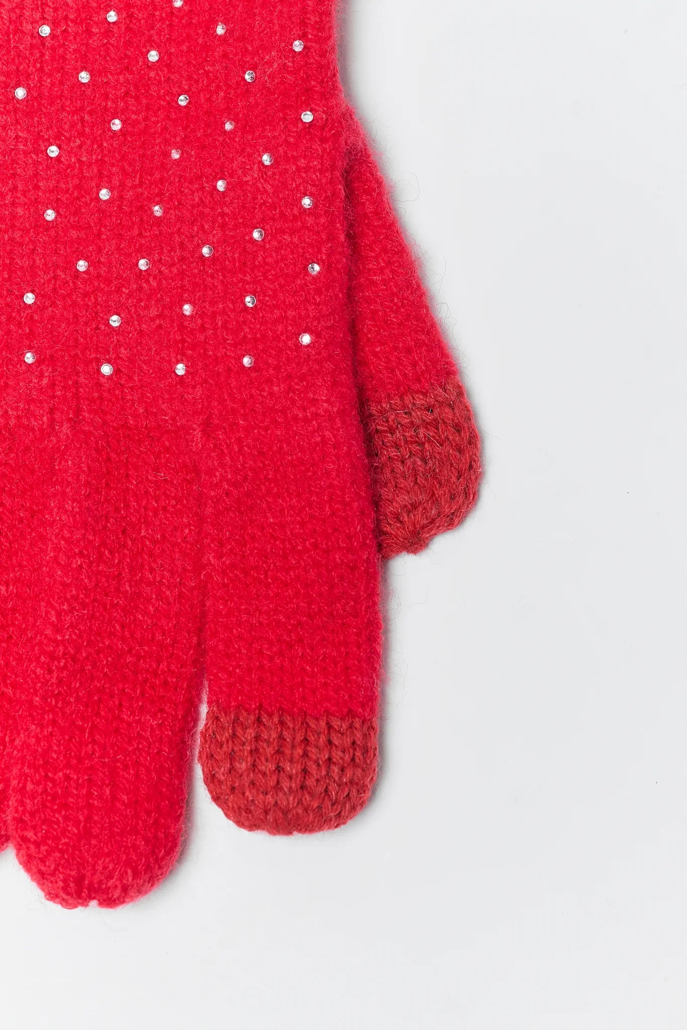 Red knitted glove with white polka dots on a light gray background