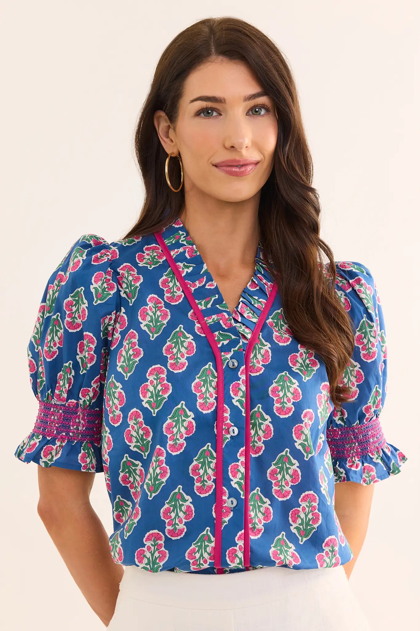 Woman wearing a blue floral blouse with pink accents on a beige background lifestyle