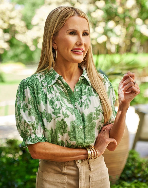 Woman wearing a green floral Mindi Top outdoors with blurred greenery in the background
