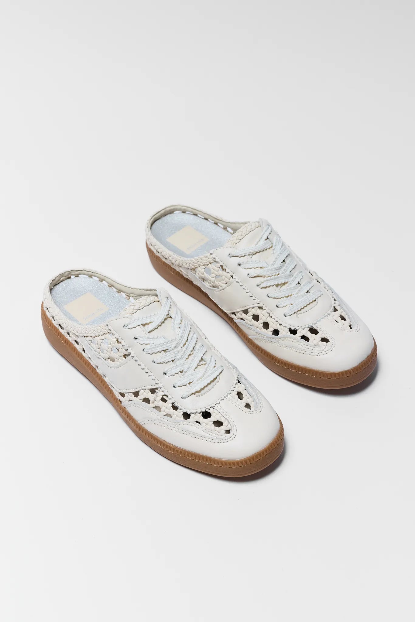 Pair of white perforated sneakers on a light gray background