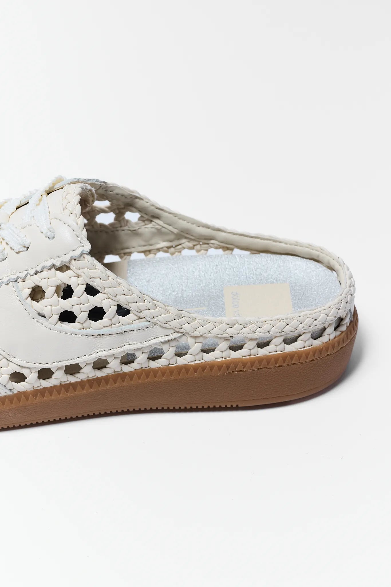 White children's shoe with brown sole on a white background