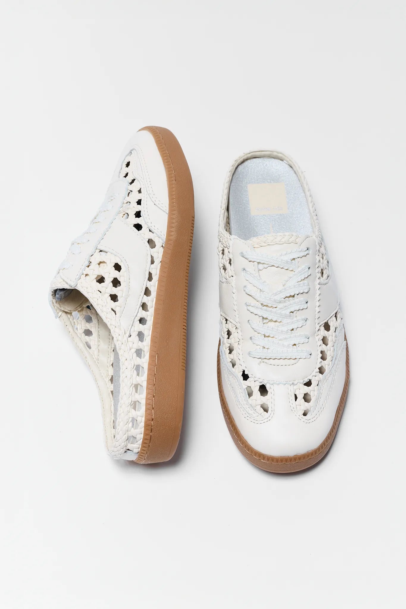 White sneakers with perforated design and brown soles on a light gray background