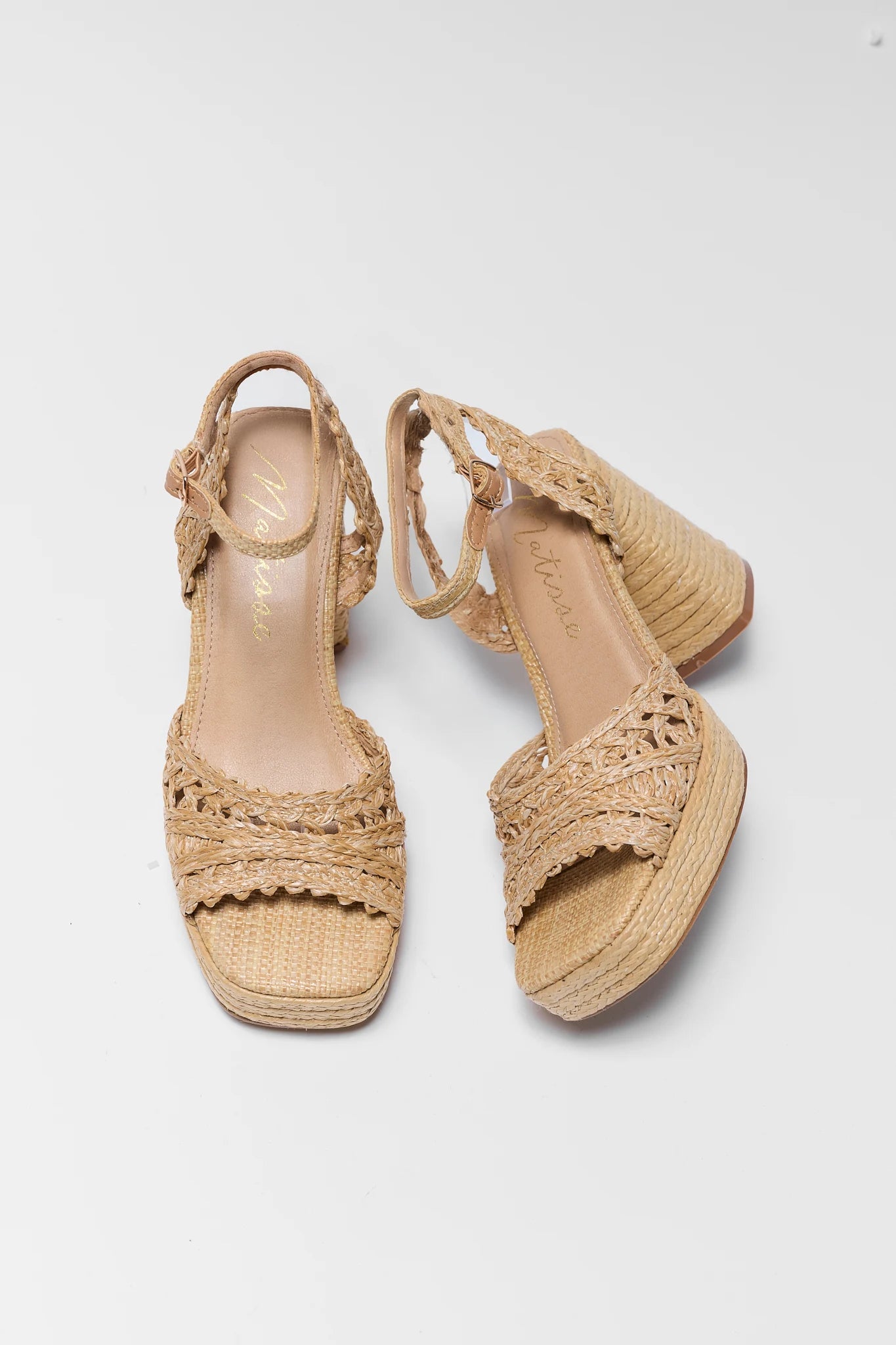 Pair of beige sandals with woven design on a white background