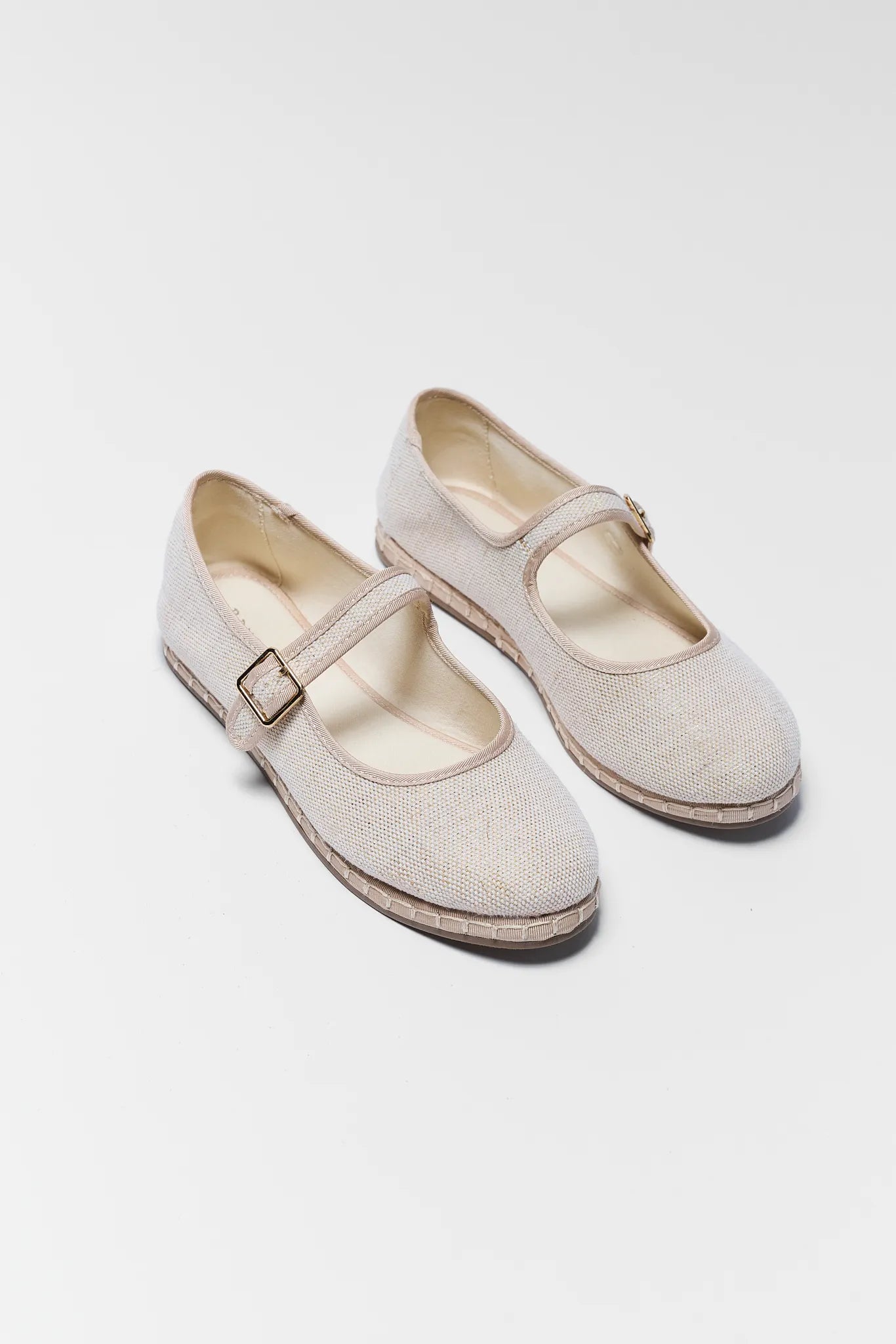 Pair of beige shoes with buckles on a white background