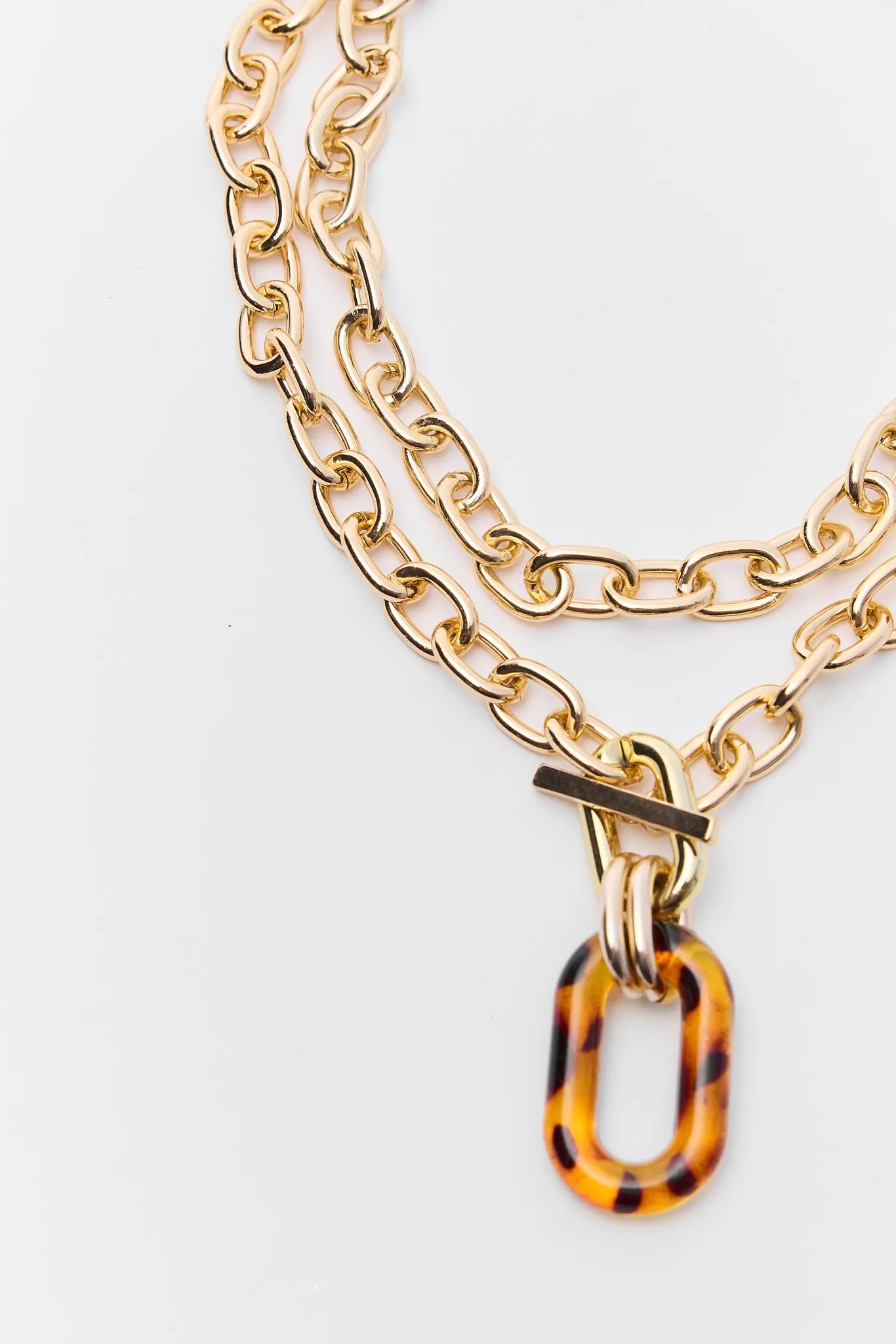 Gold chain necklace with a tortoiseshell accent on a white background