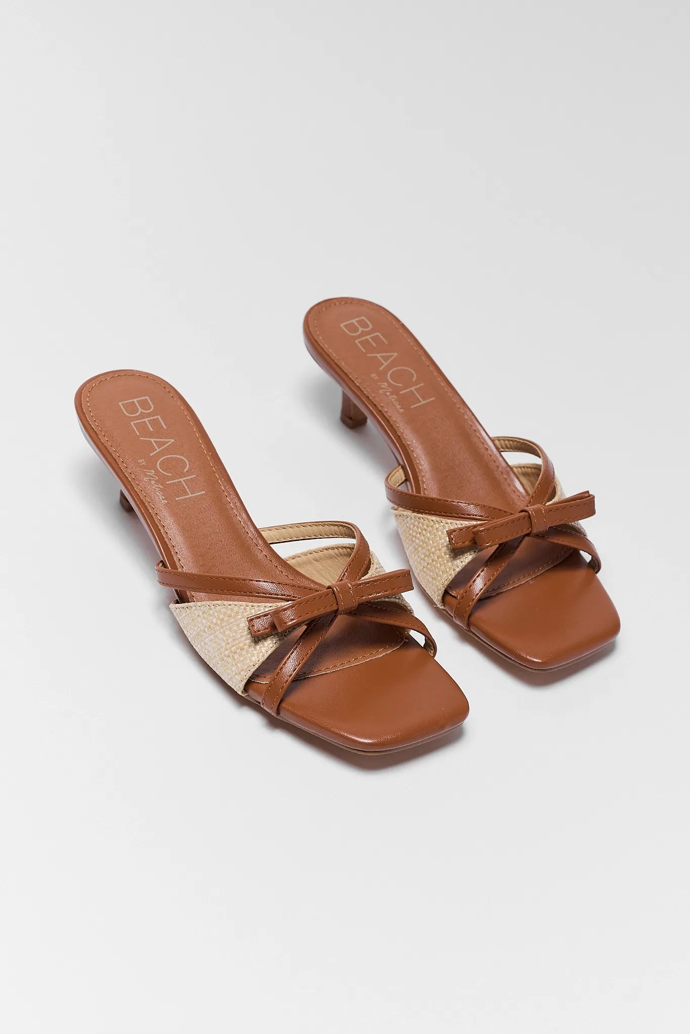 two Portia Brown Raffia Kitten Heels on white background