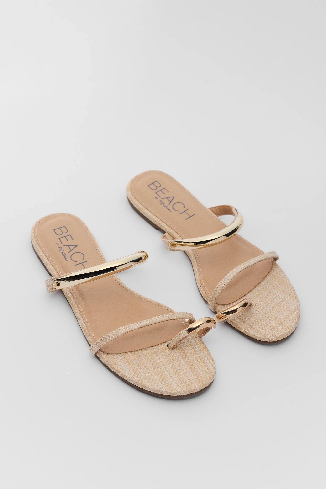 Pair of two beige sandals with gold straps on a light gray background