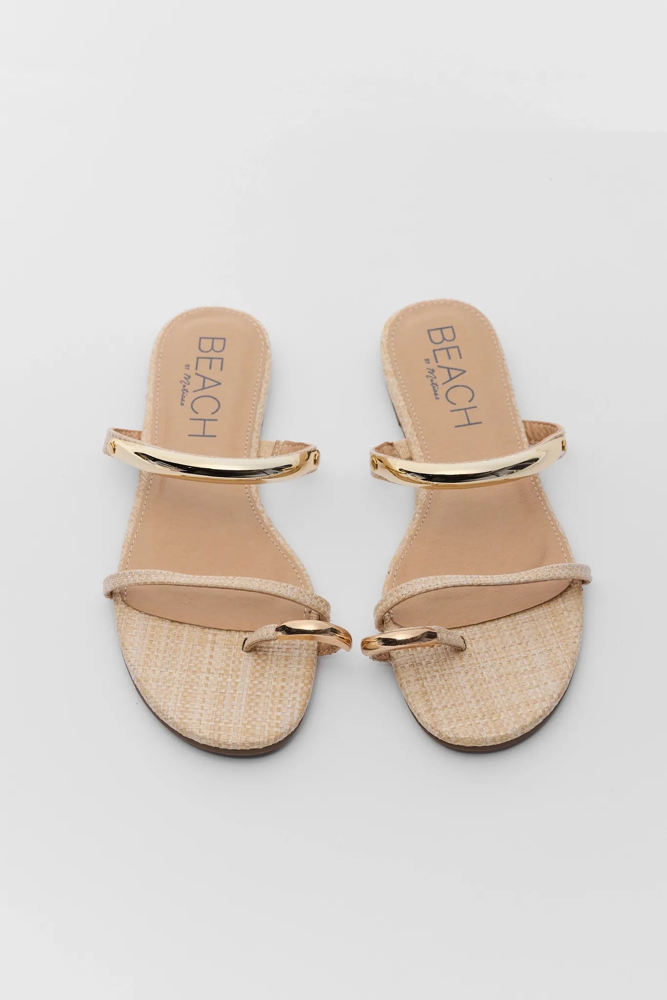 Pair of beige sandals with gold straps on a light gray background two