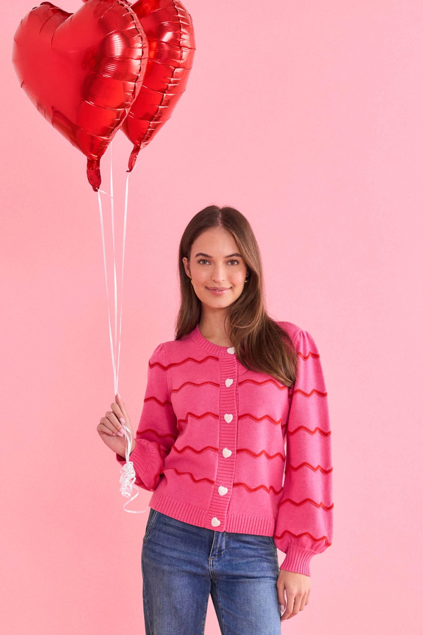 woman holding balloons on a pink background