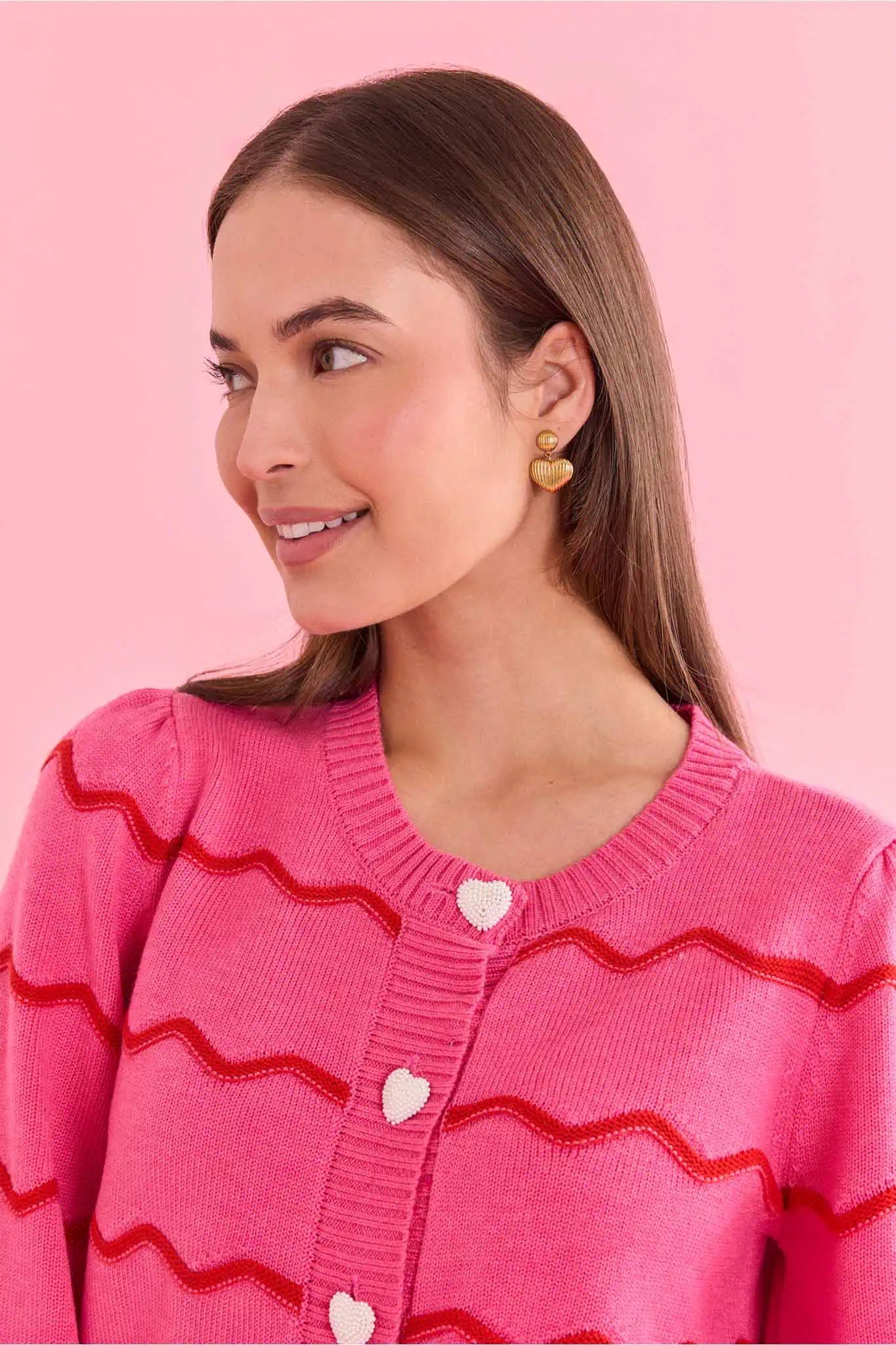 woman wearing pink sweater with heart buttons on a pink background