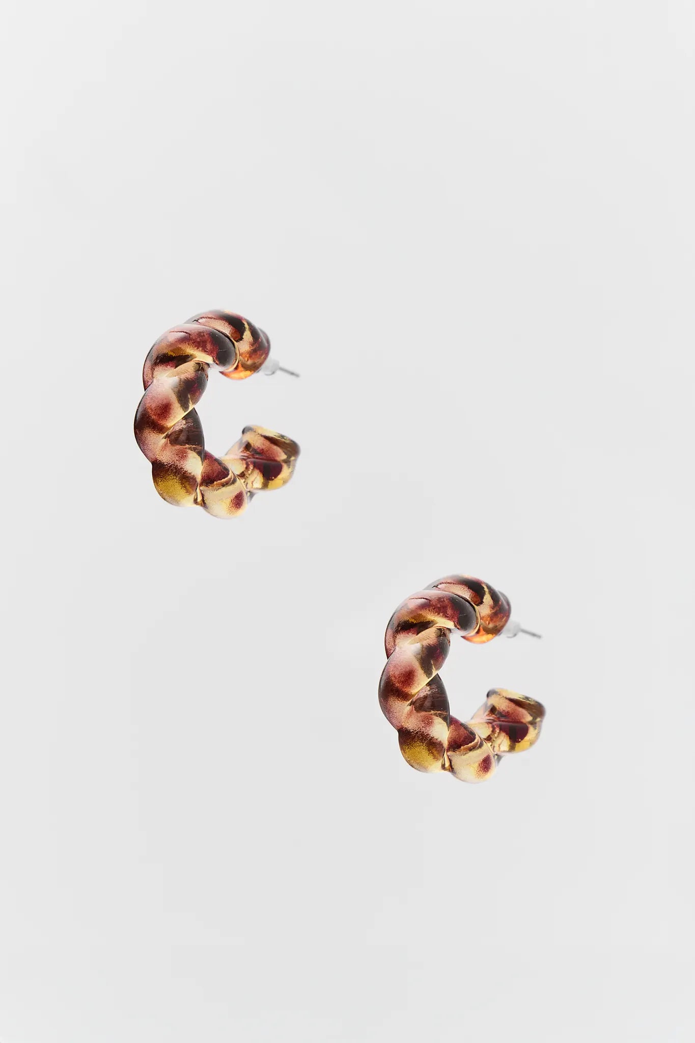 Pair of tortoiseshell hoop earrings on a light gray background