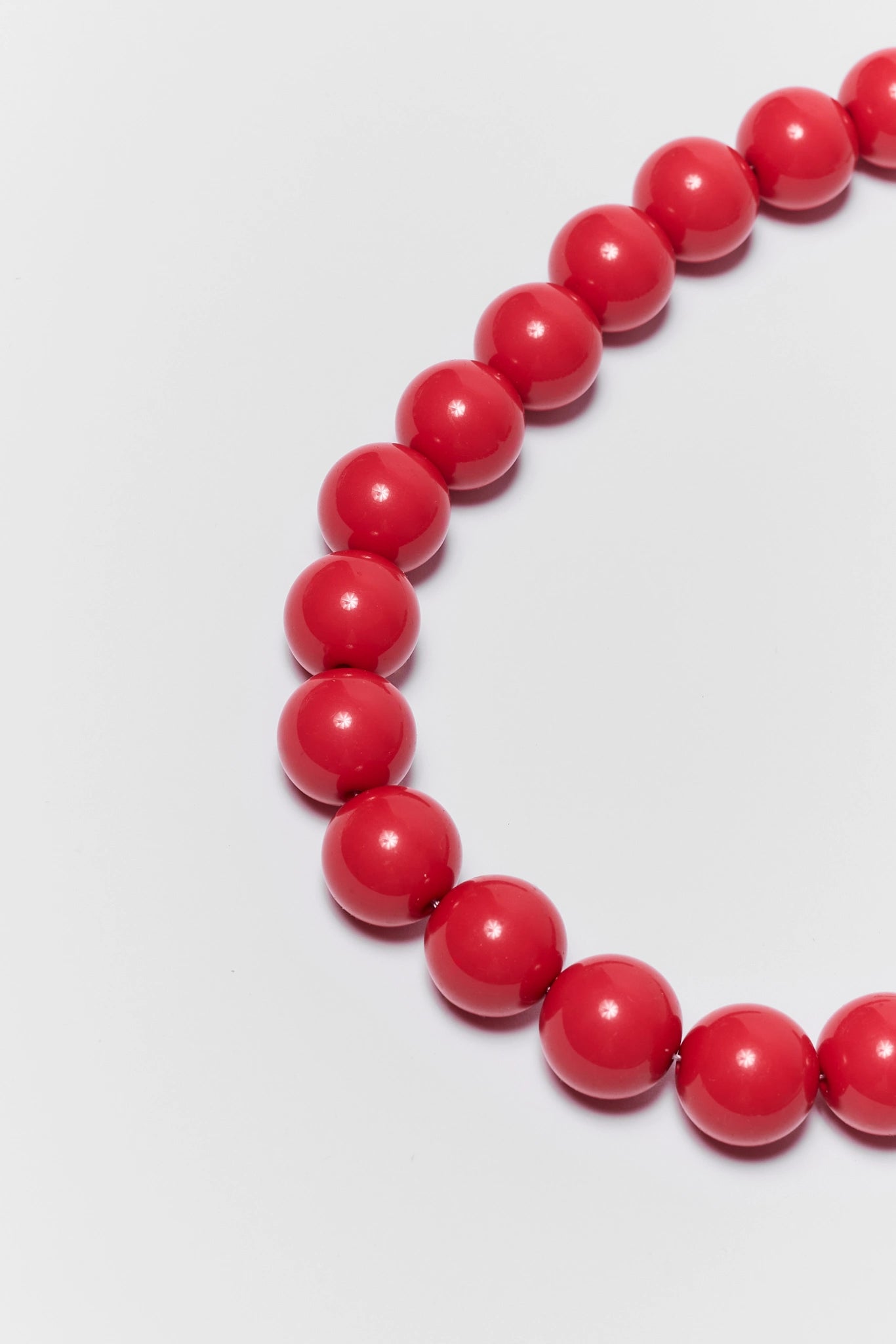 close up red beaded bracelet on a light gray background