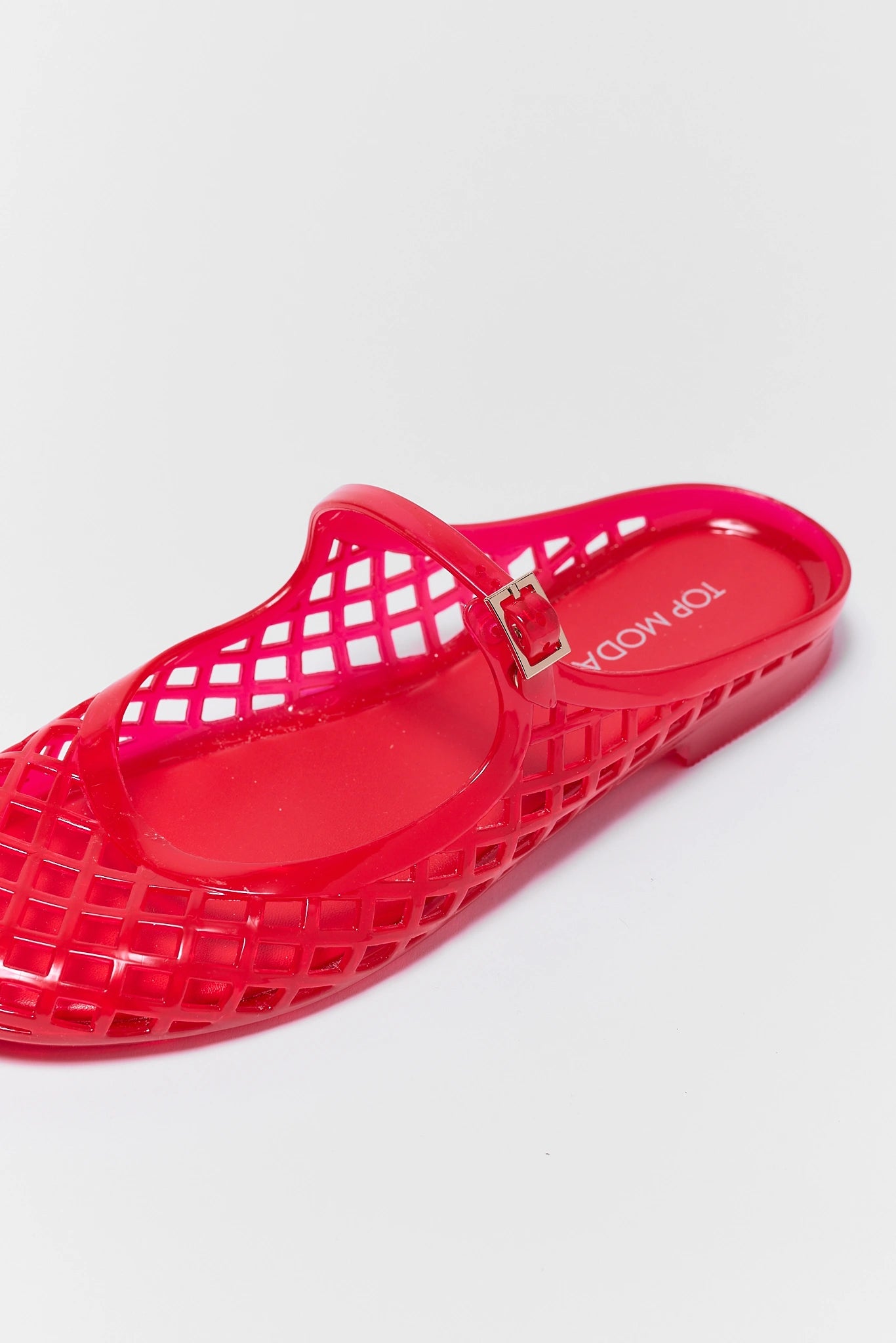 close up red jelly sandal with a buckle on a light gray background