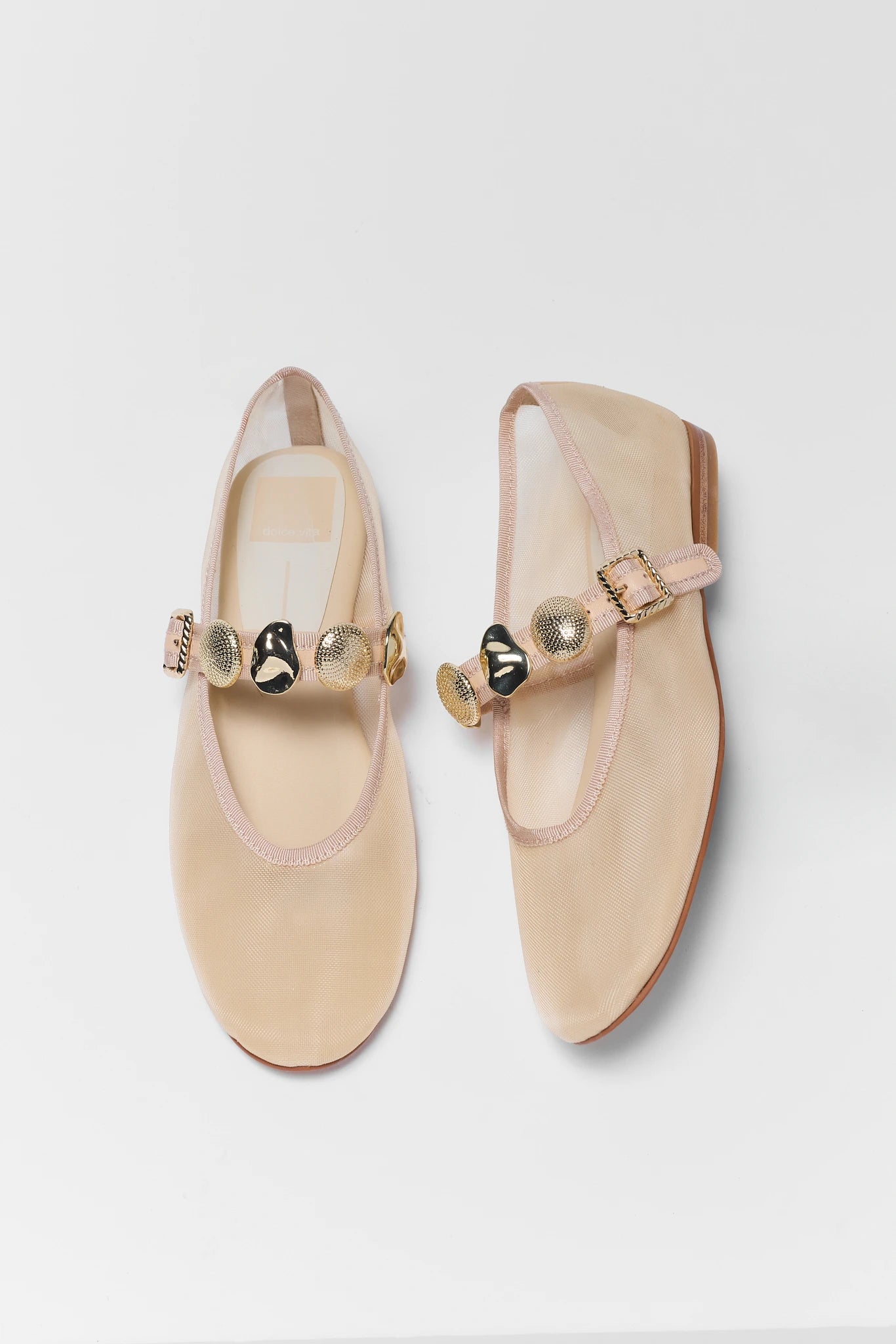 Pair of beige shoes with decorative bows on a light gray background