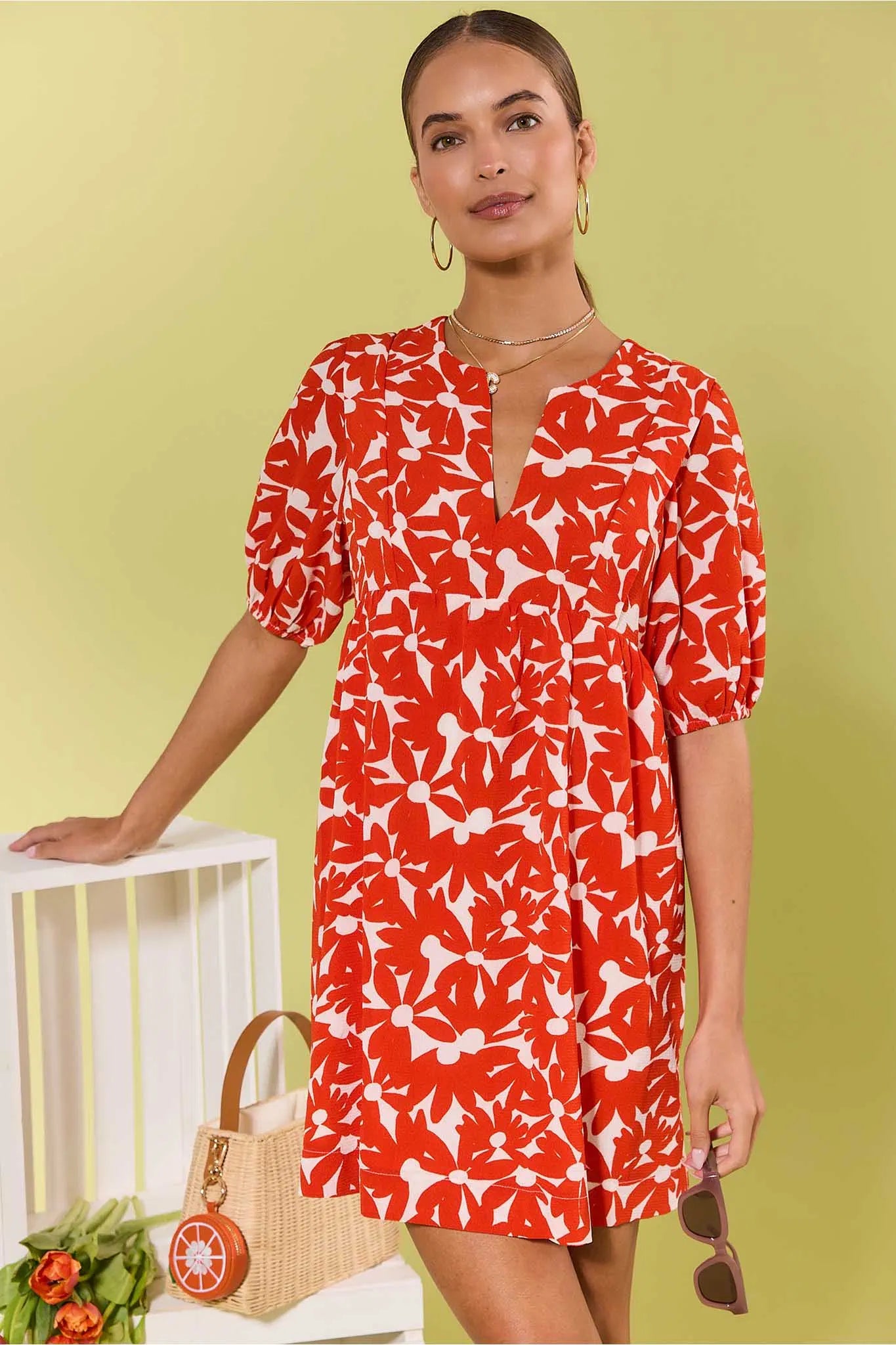 Woman wearing a red floral dress against a light green background