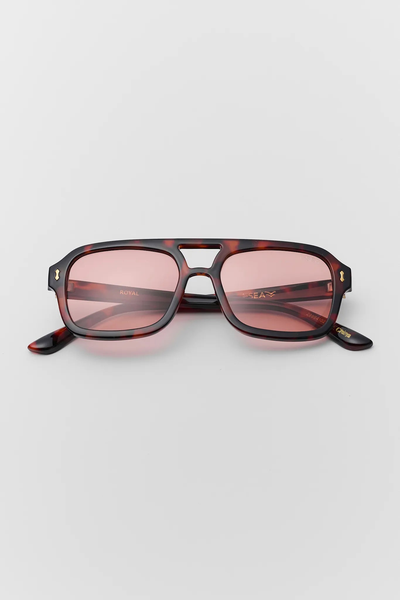 Sunglasses with tortoiseshell frame and pink lenses on a light gray background