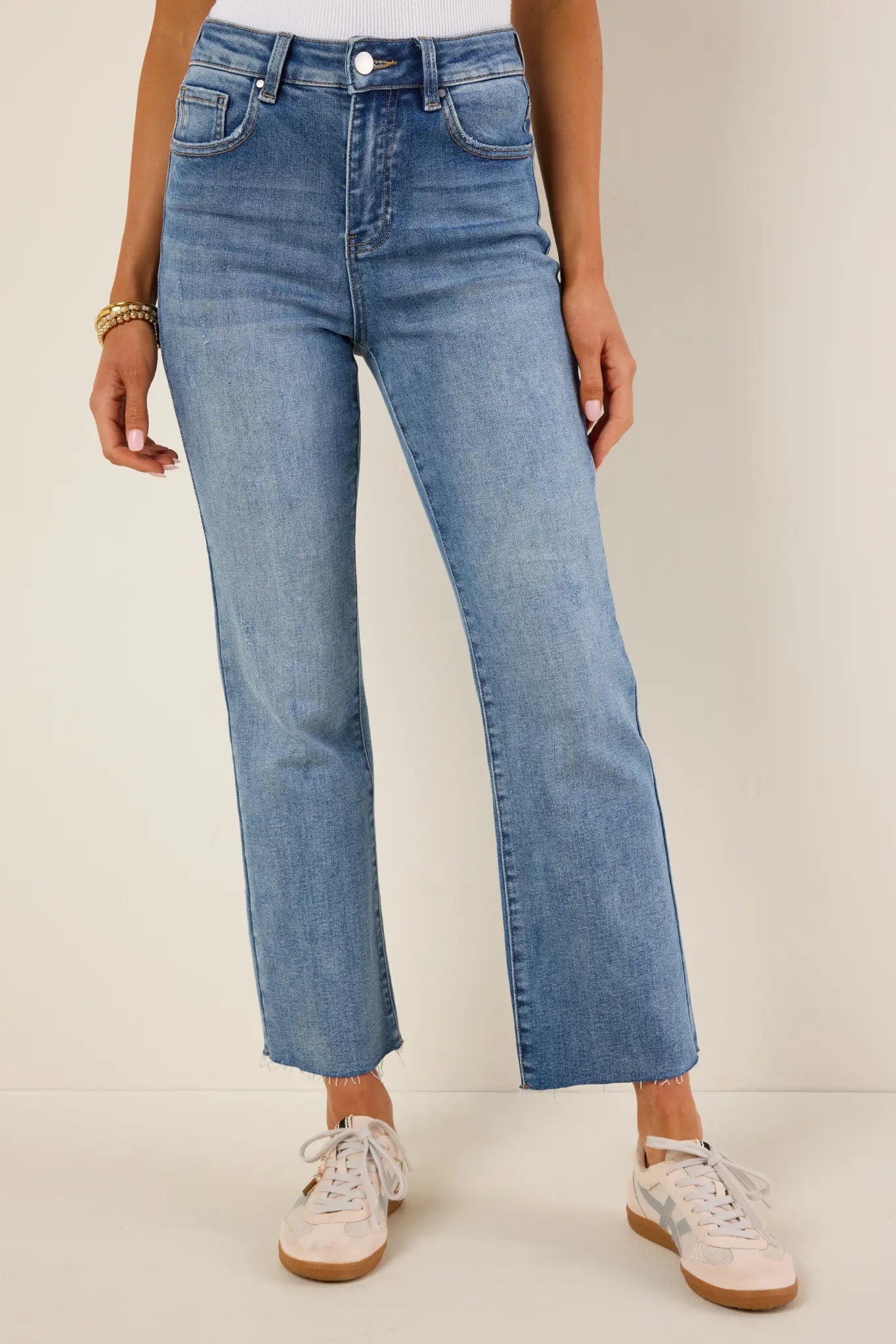 Person wearing light blue Aliyah jeans and white sneakers on a plain background