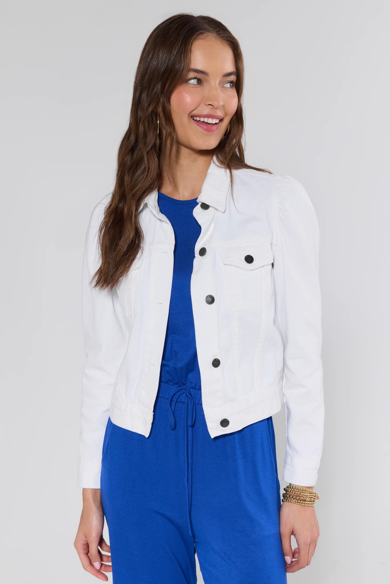 View 2: Woman wearing a white jacket over a blue outfit on a plain background