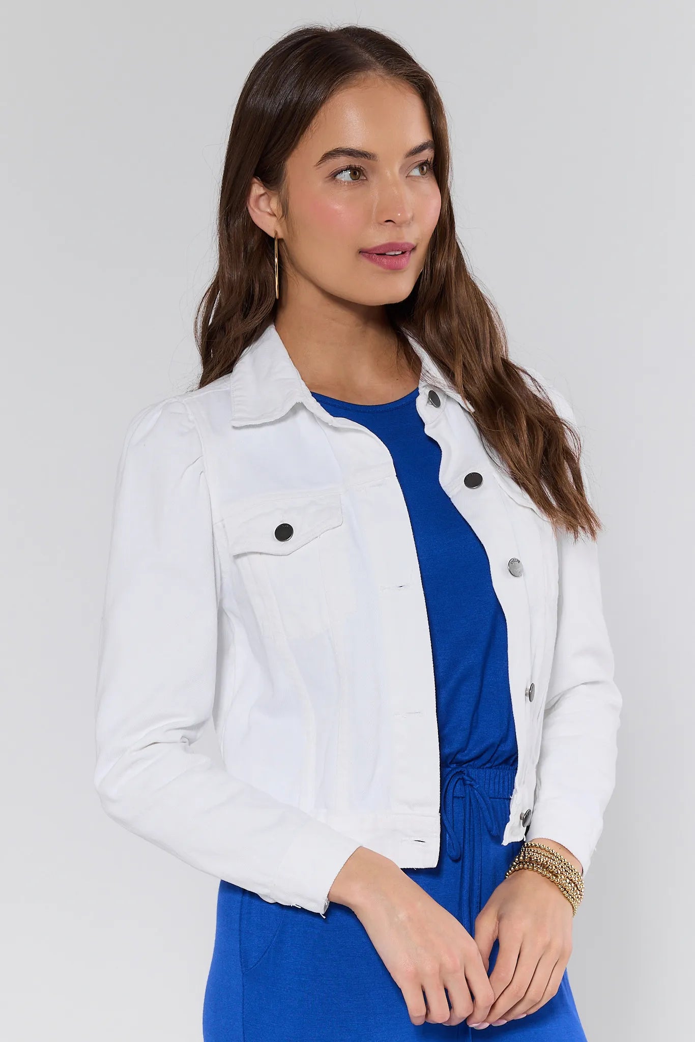 Woman wearing a white denim jacket over a blue dress on background