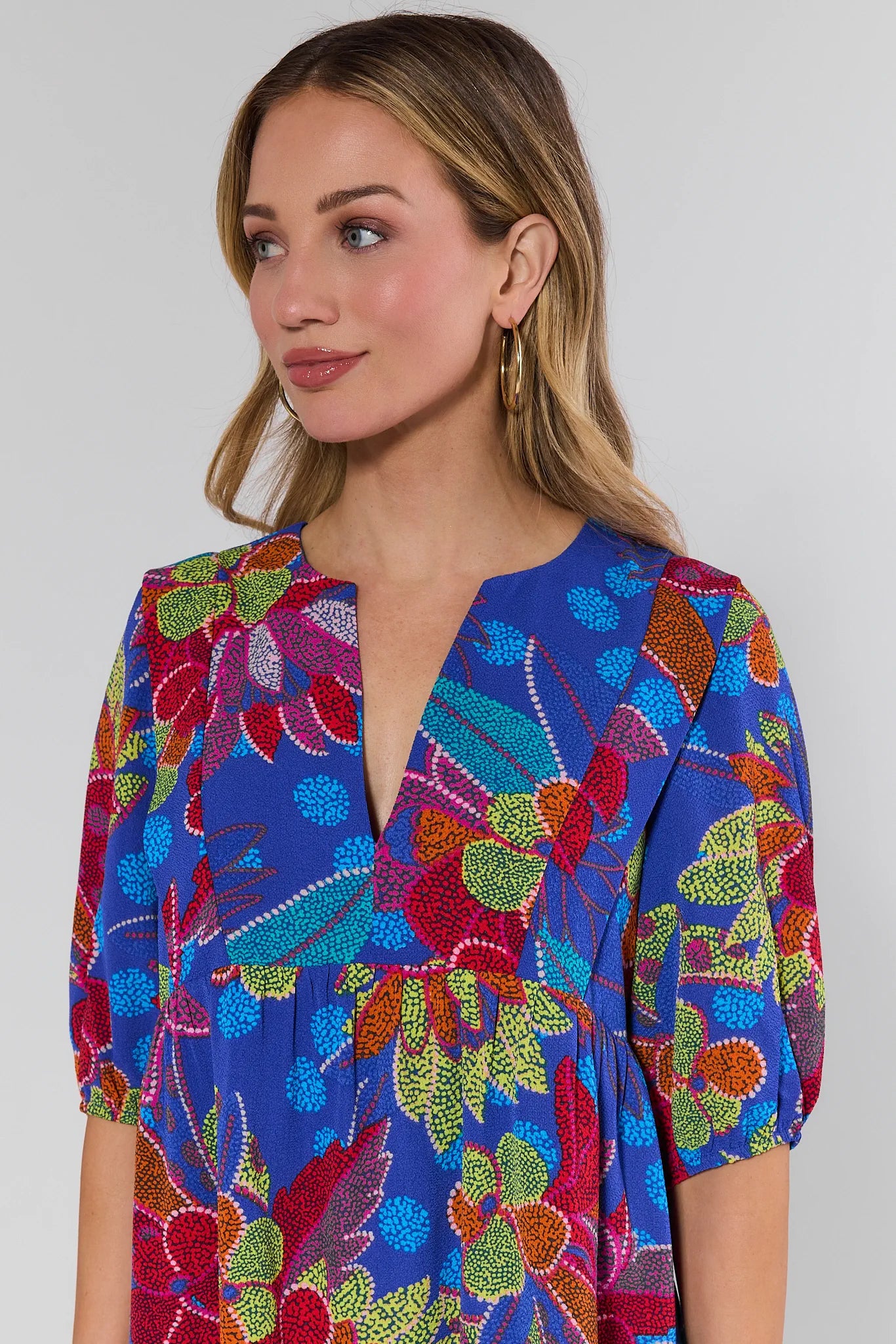 Woman wearing a colorful patterned dress against a plain background