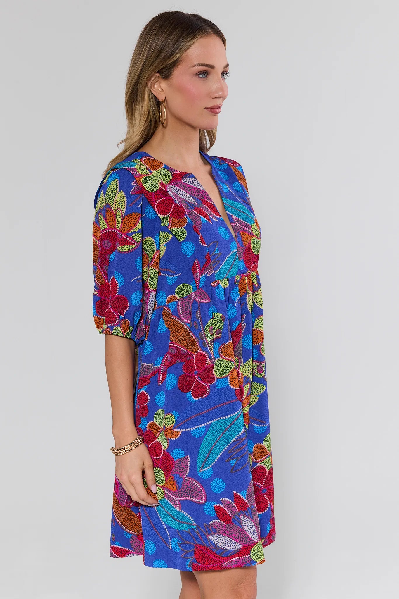 Woman wearing a colorful floral dress against a white background