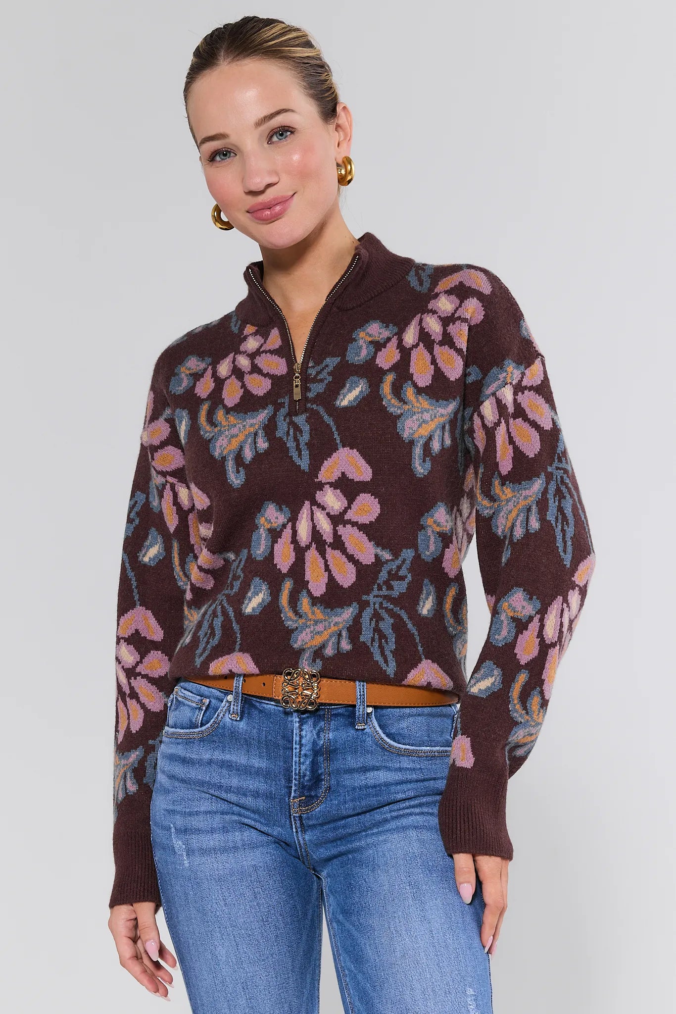 Woman wearing a floral patterned Nancy Sweater Brown and blue jeans on a white background