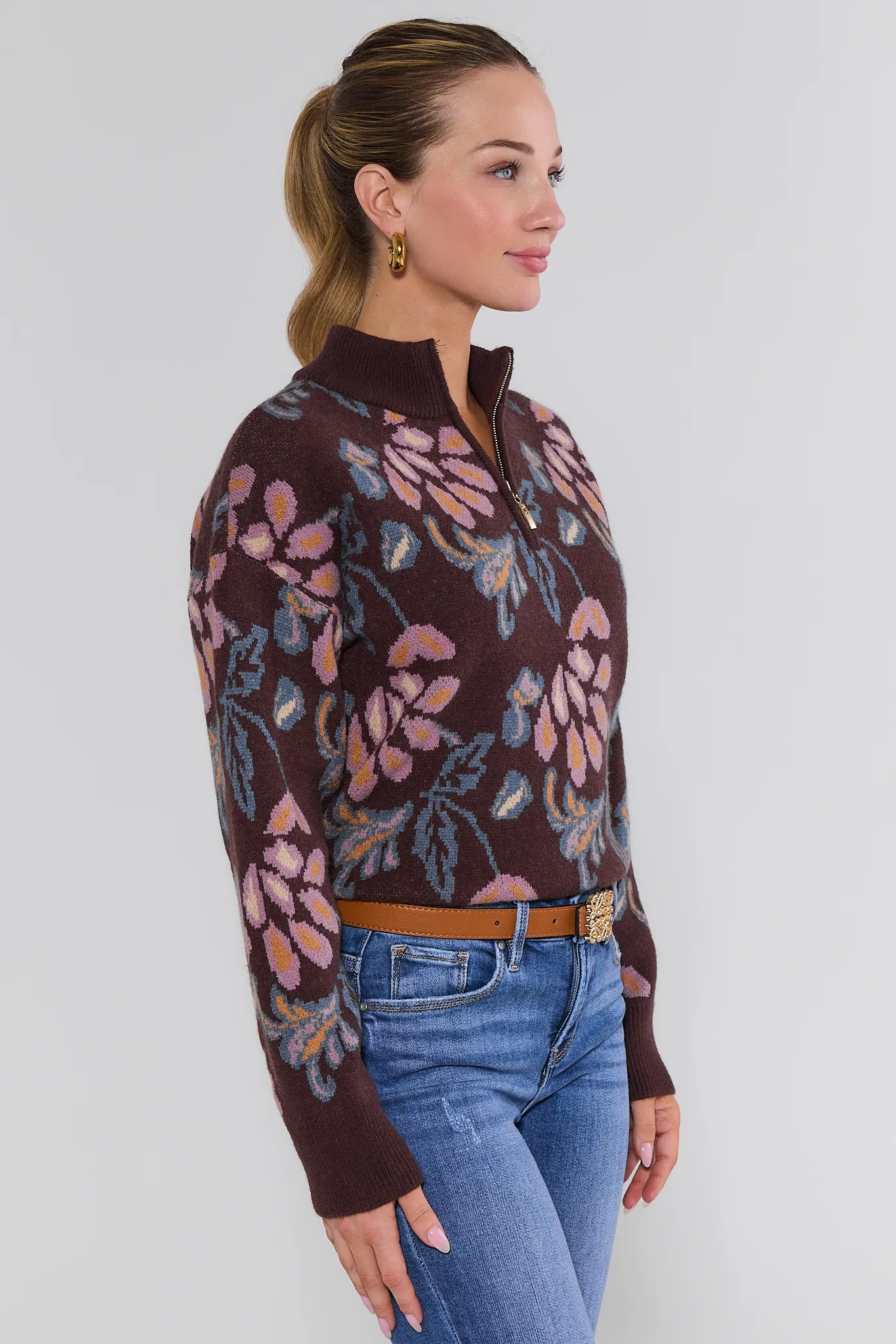 Woman wearing a floral-patterned Nancy Sweater Brown and blue jeans against a white background