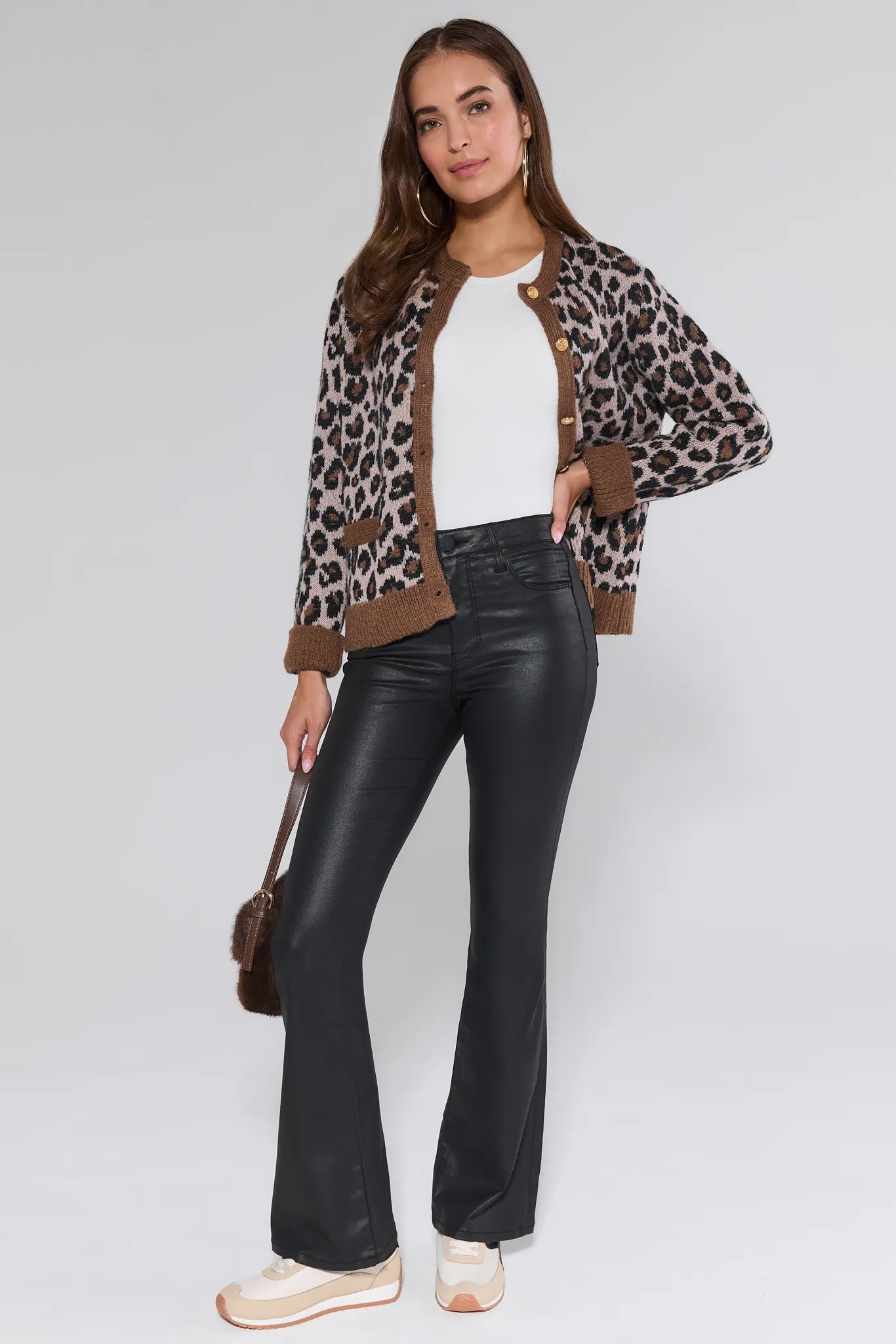 Woman wearing a leopard print jacket, white top, black Ana Jeans Wax Coated, and beige shoes on a white background