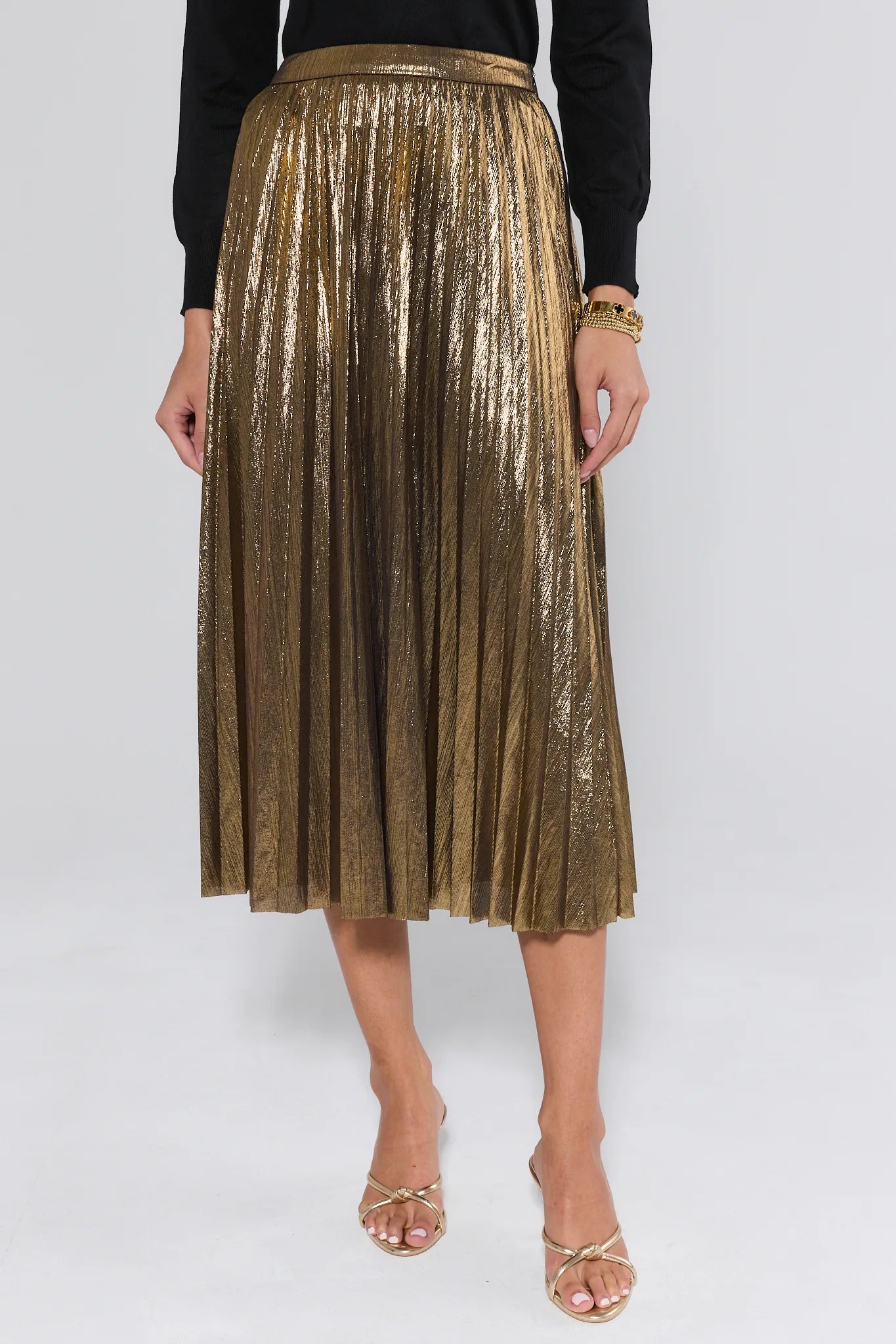 Gold pleated skirt worn by a person on a white background