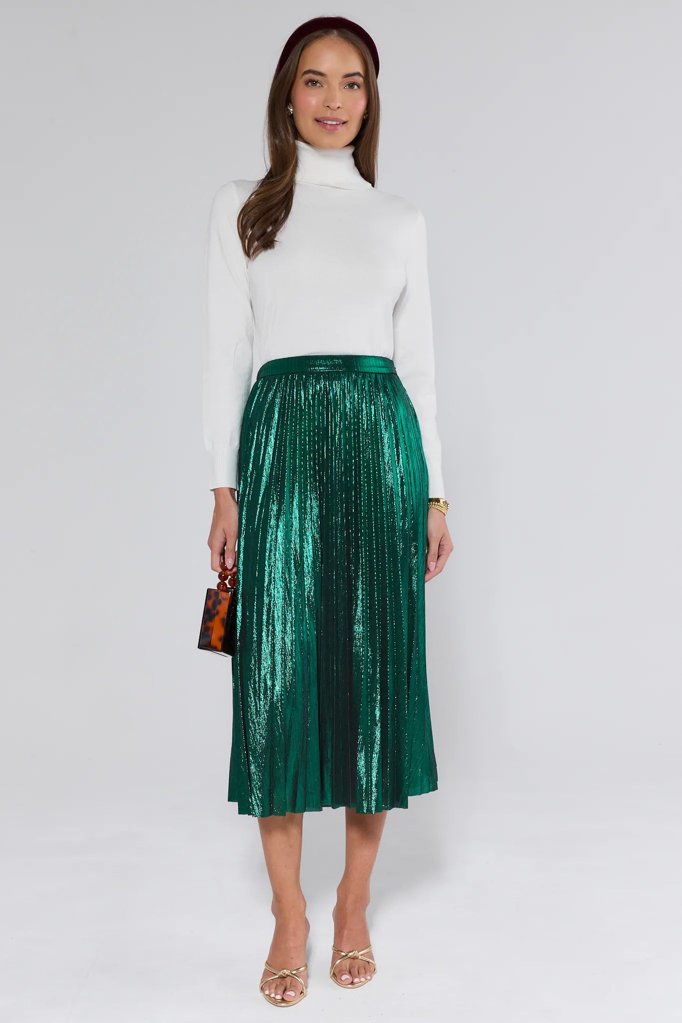 Woman wearing a white turtleneck and green metallic skirt on a white background
