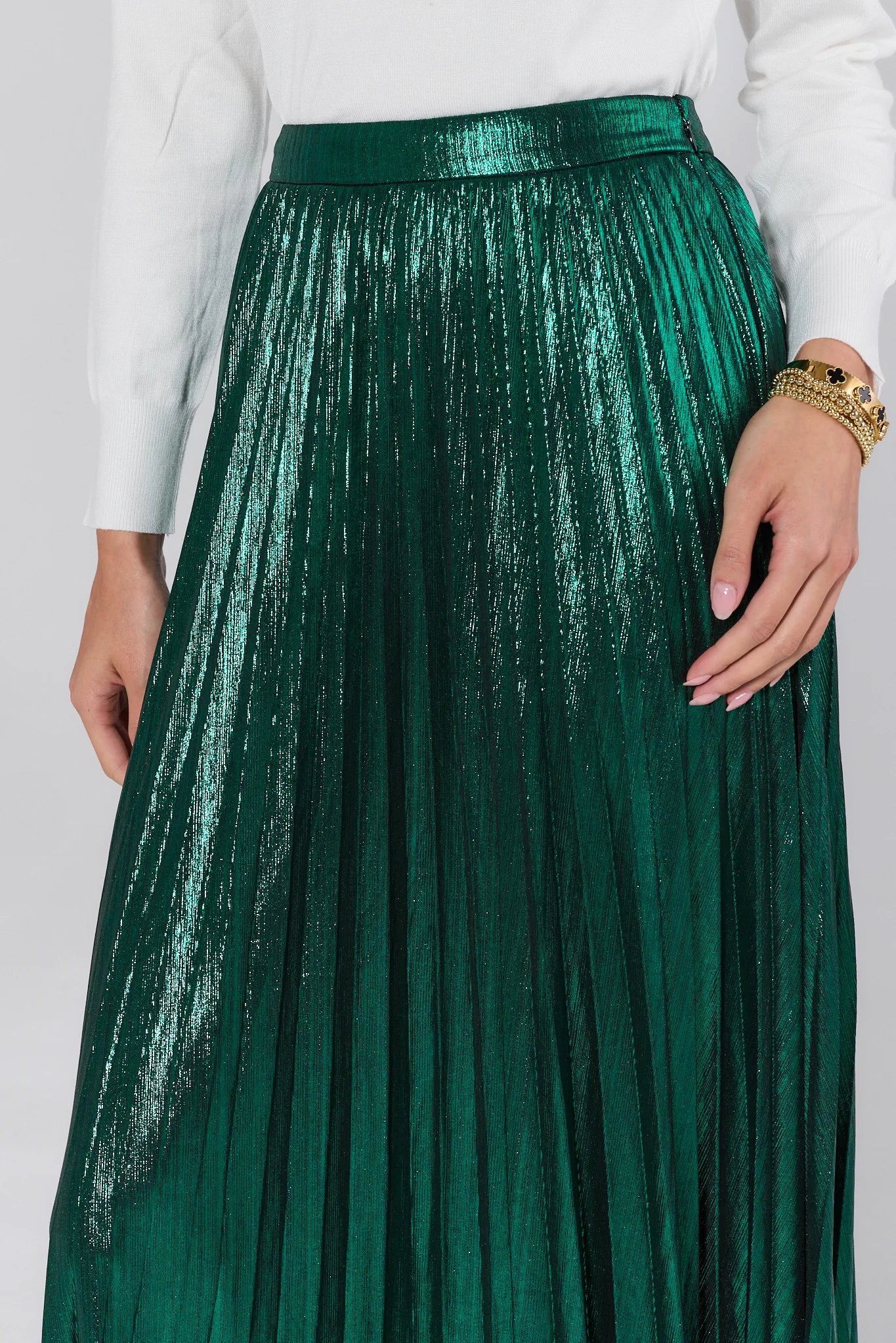 Green pleated skirt worn with a white top on a plain background