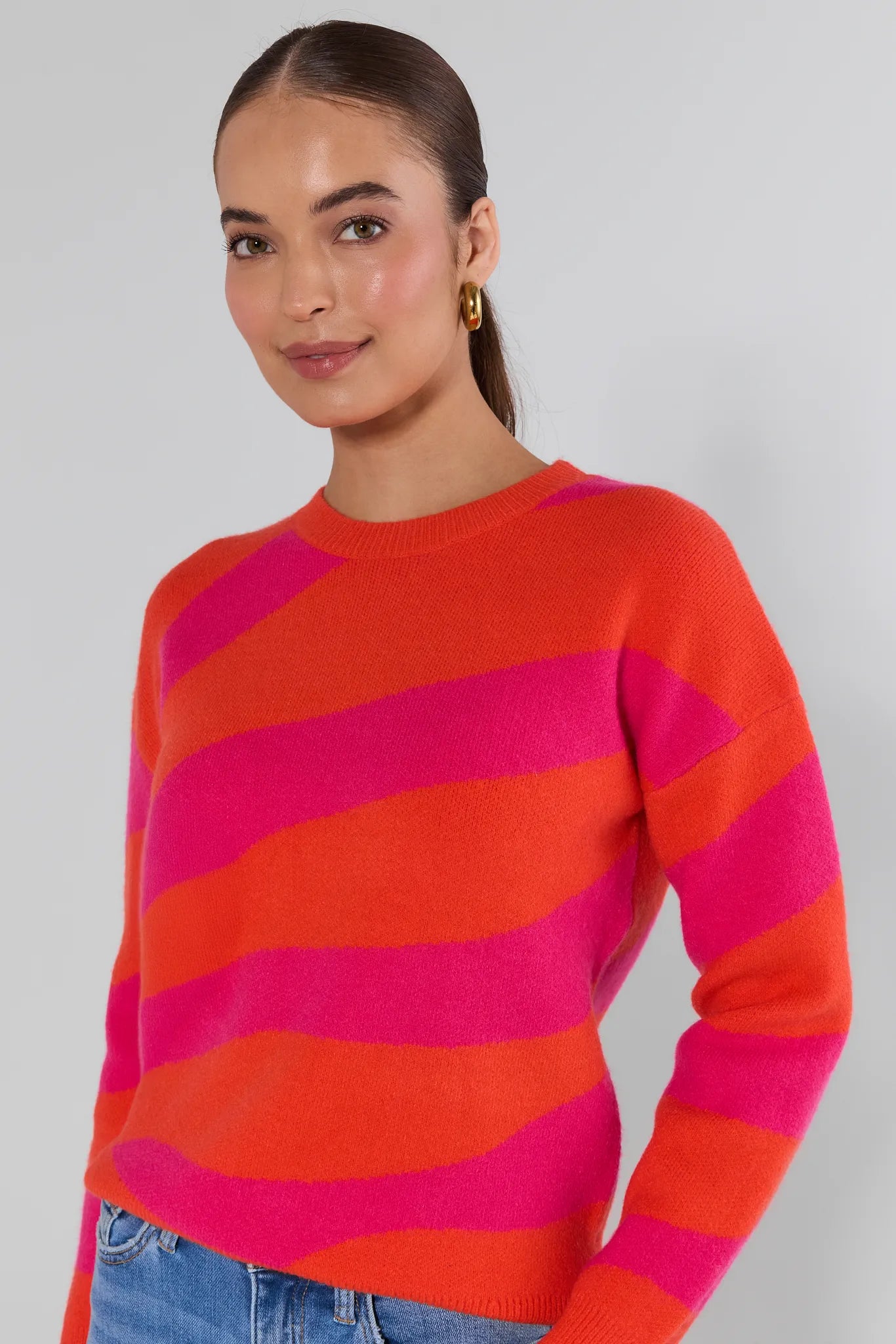 Woman wearing a red and pink striped sweater against a plain background