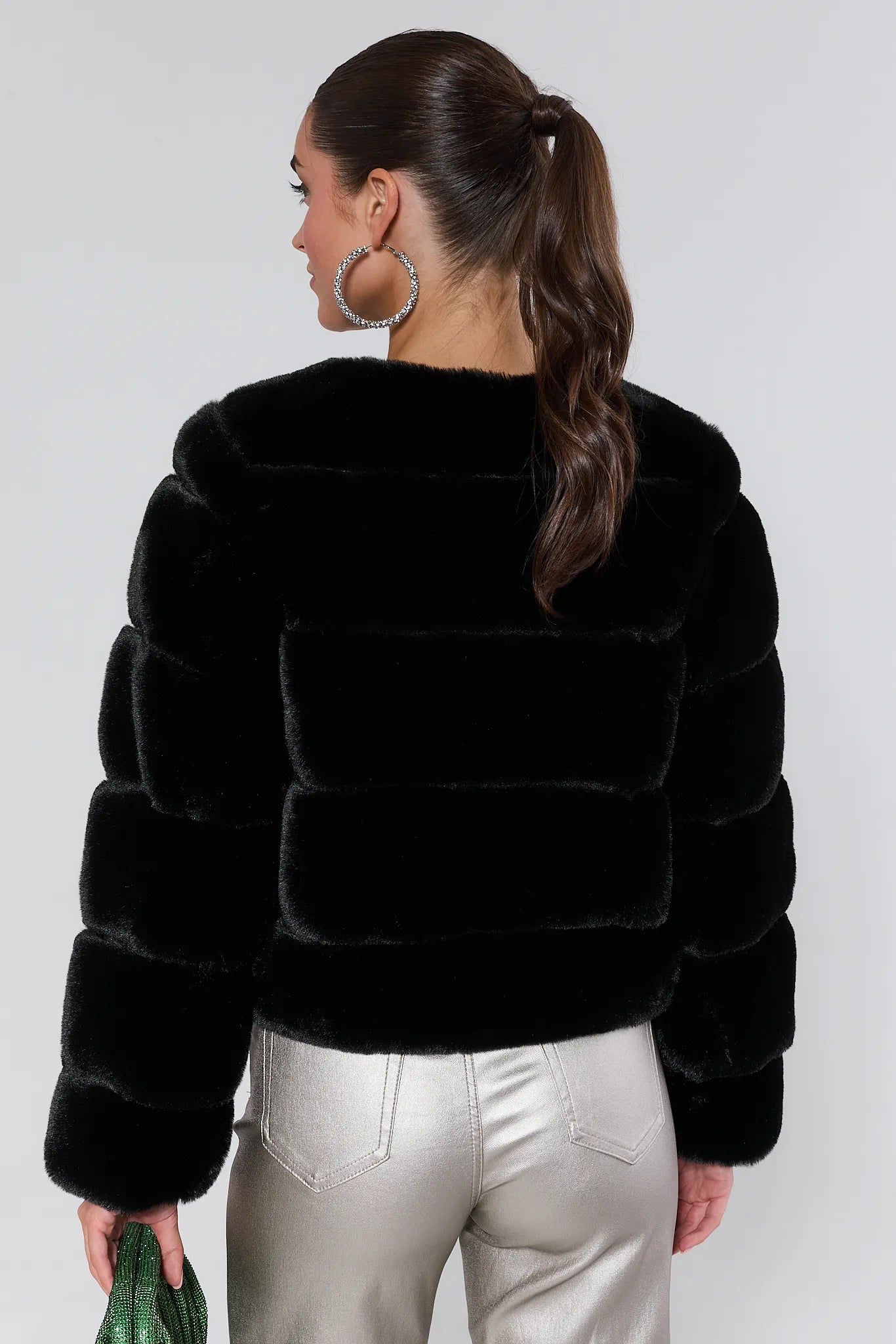 Woman wearing a Janet Black Faux Fur Jacket and silver pants on a white background