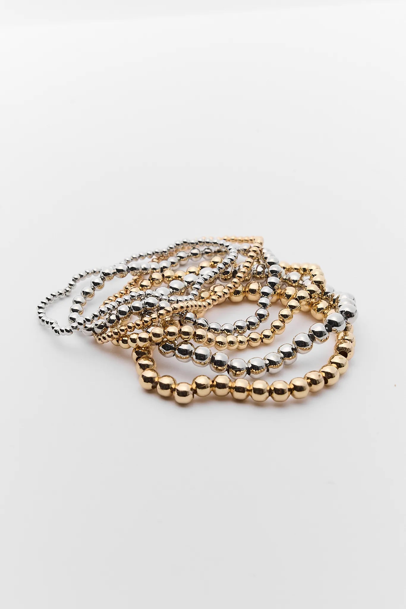 Set of gold and silver beaded Maisie bracelets on a light gray background