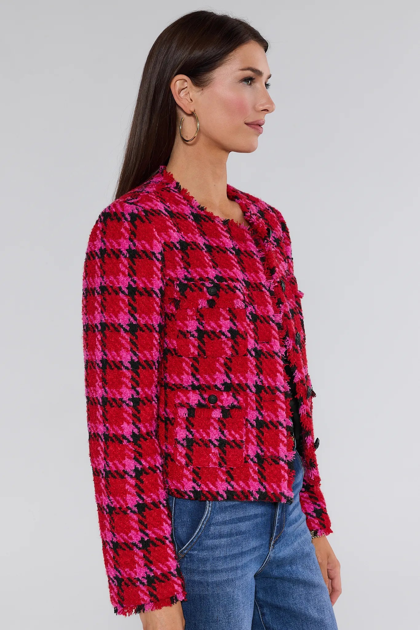 Woman wearing a red and black checkered maryl jacket with blue jeans on a white background