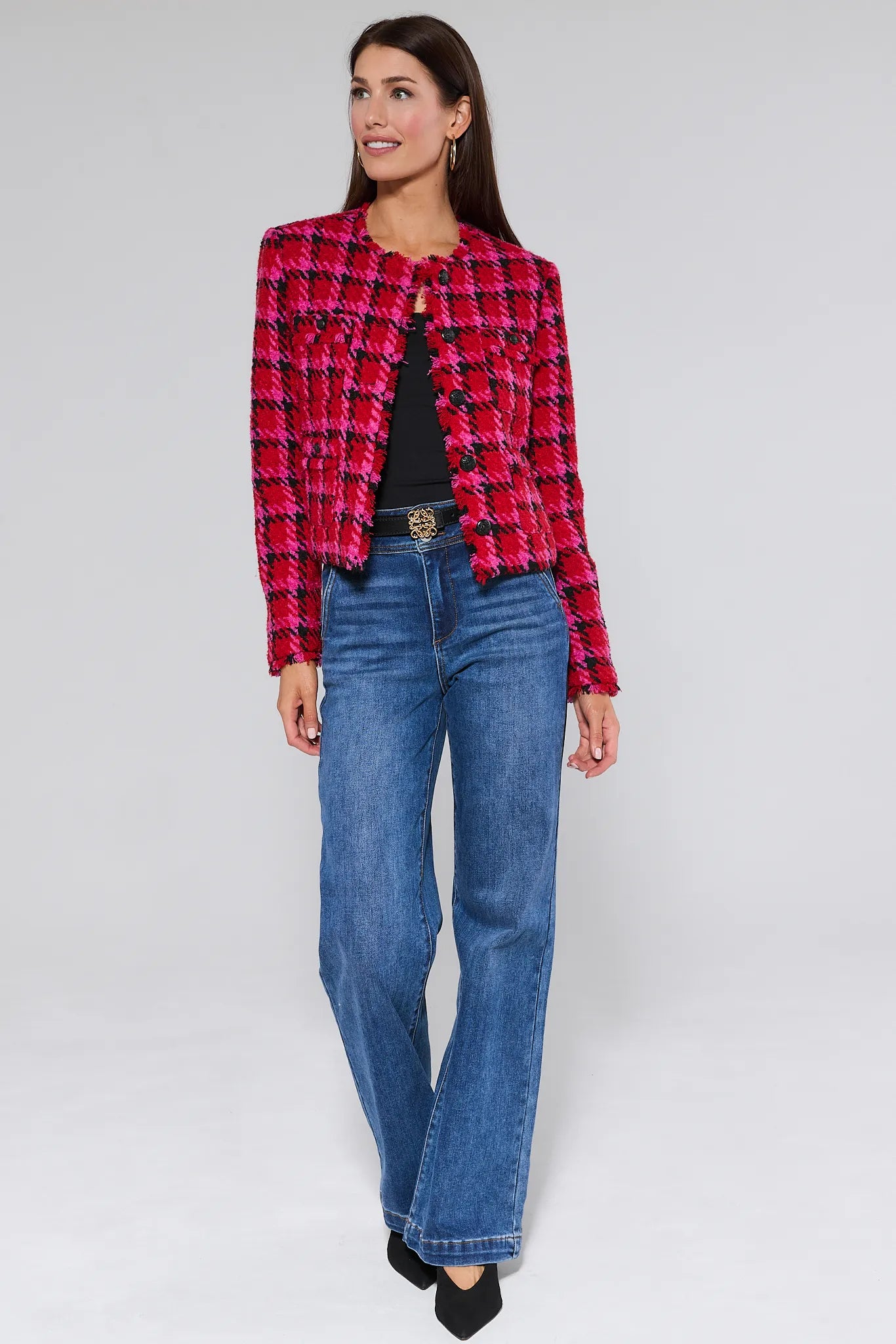 Woman wearing a red and black checkered maryl jacket with blue jeans on a white background