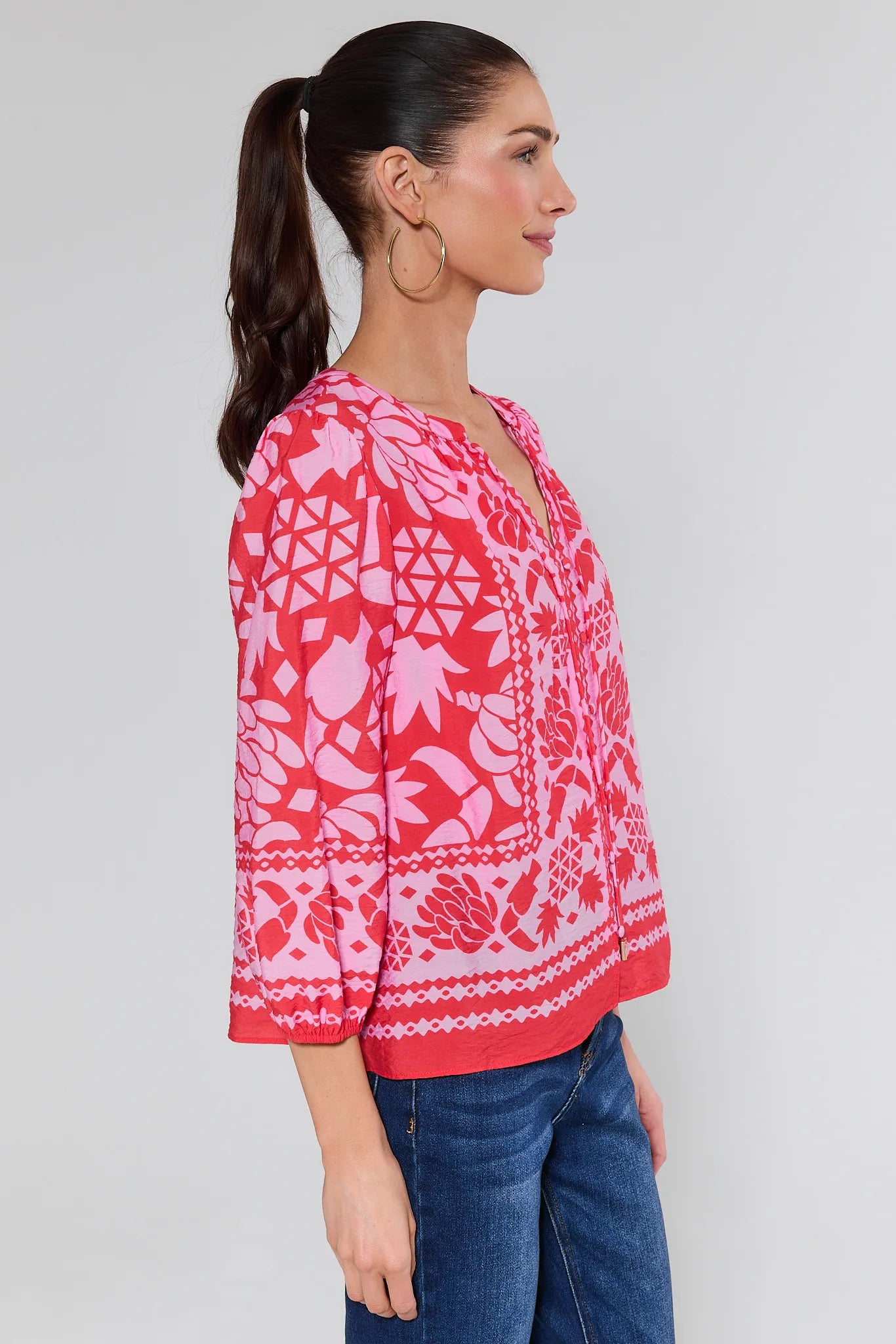 Woman wearing a pink patterned blouse with jeans on a white background