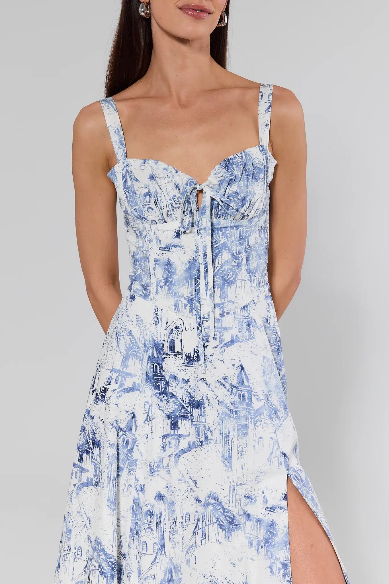 Woman wearing a blue and white floral dress against a gray background