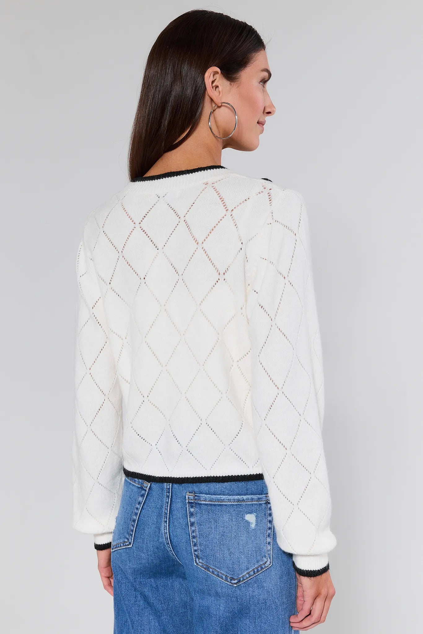 Woman wearing a Maxine Embroidered Pointelle Cardigan and button details on a plain background