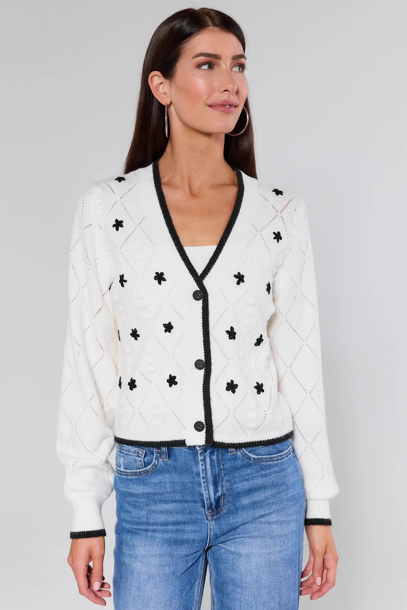 Woman wearing a Maxine Embroidered Pointelle Cardigan and button details on a plain background