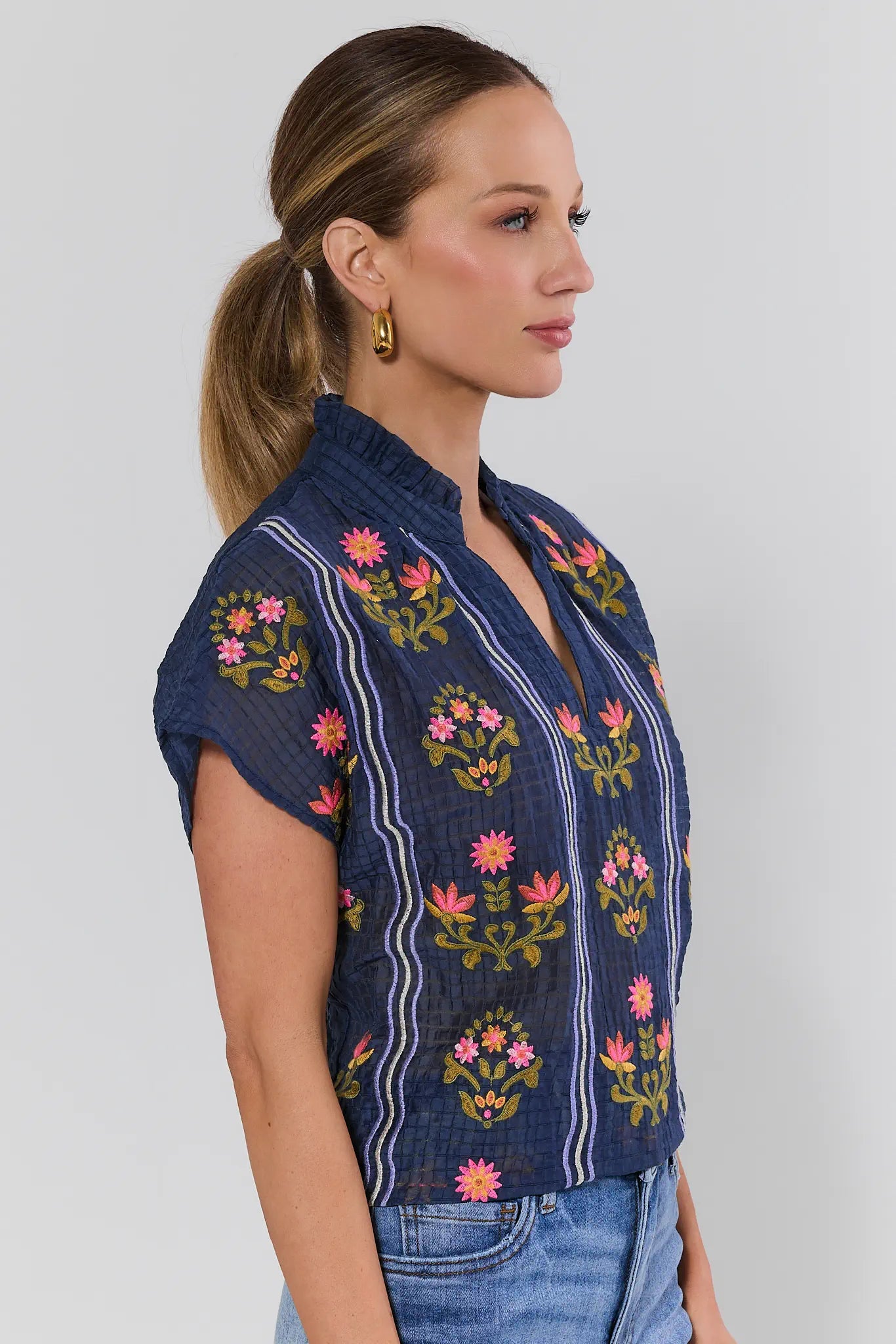 Woman wearing a blue embroidered top with floral on a background