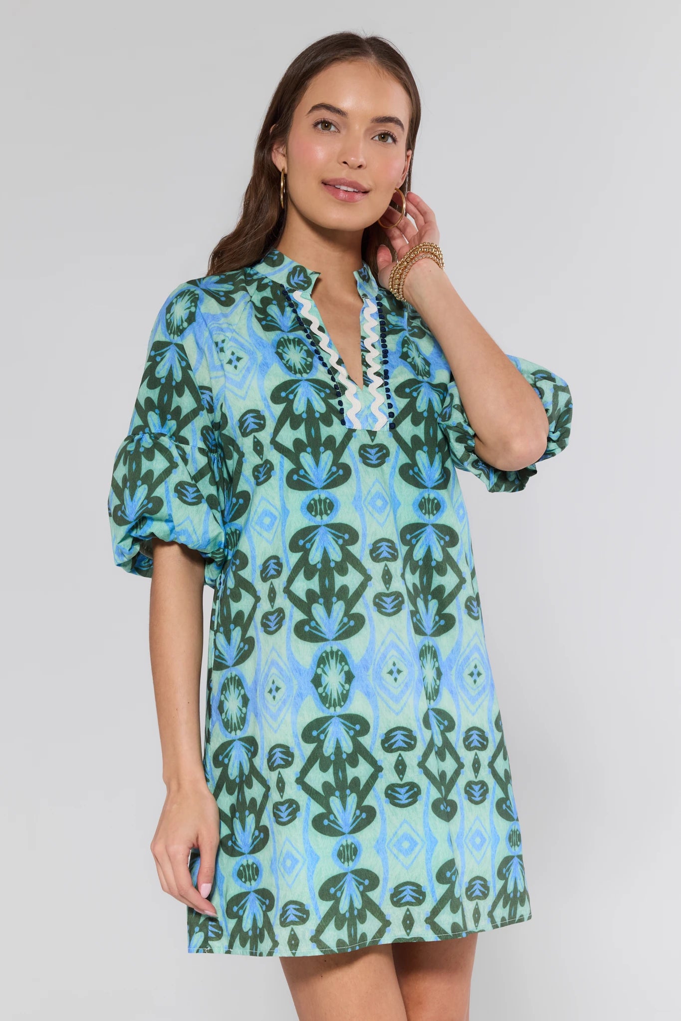 Woman wearing a blue and green patterned dress on a white background