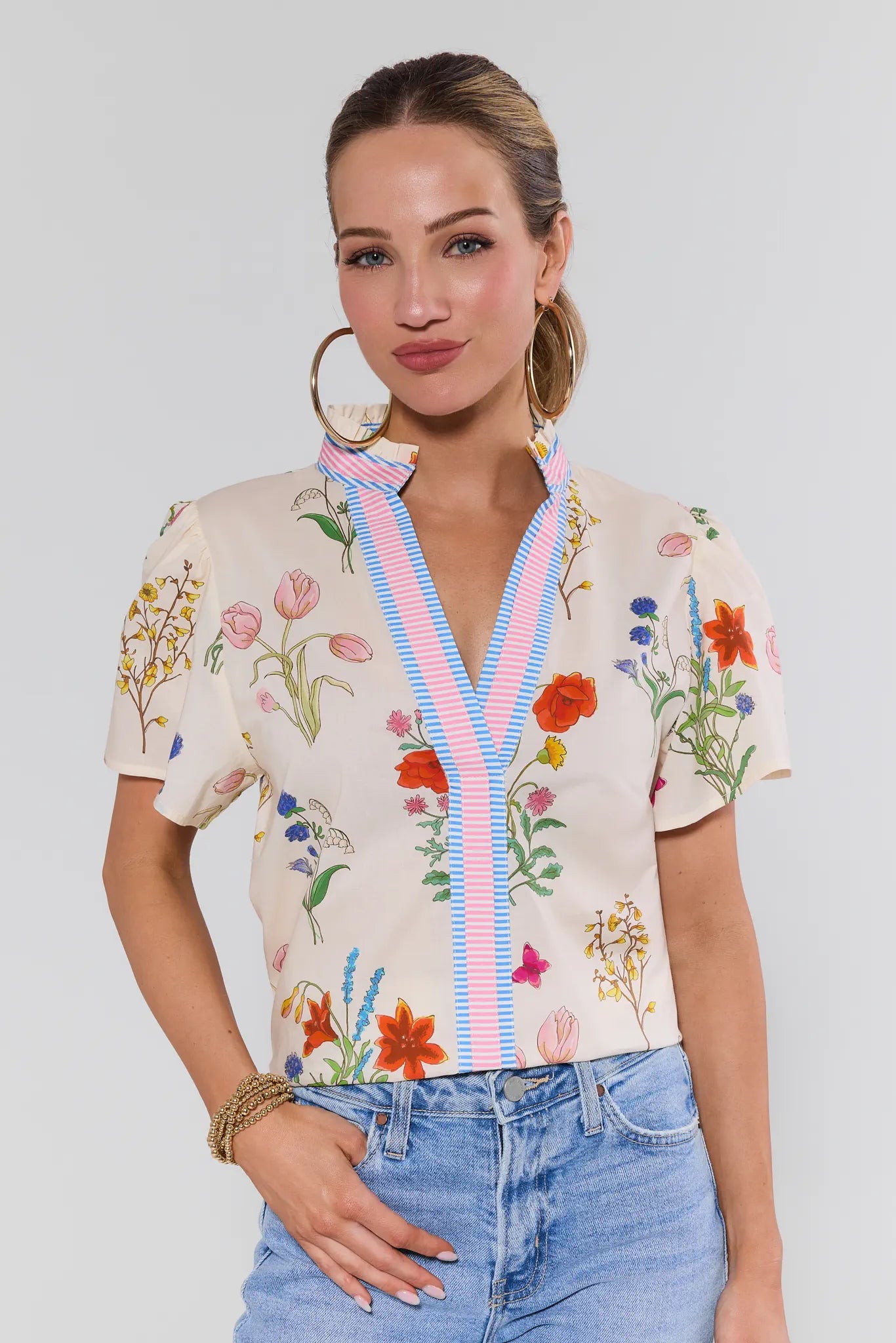 Woman wearing a floral blouse with a colorful ribbon and jeans on a plain background