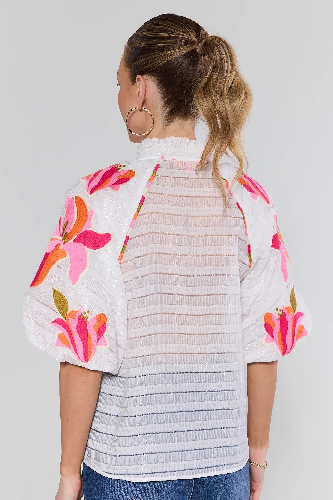 Woman wearing a floral blouse with a striped pattern on a plain background